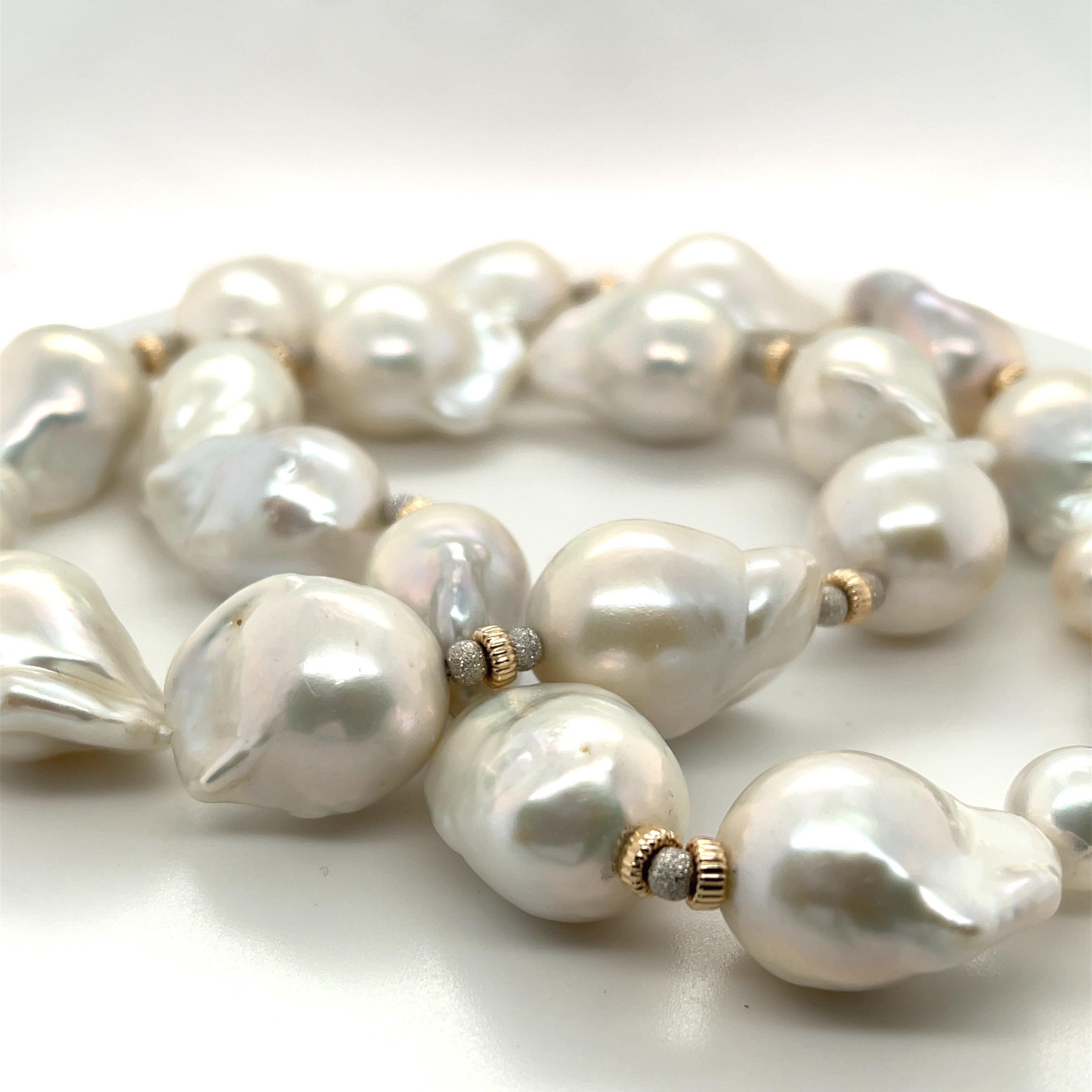 This impressive necklace features 19 large white baroque freshwater nucleated pearls ranging in size from 14 to 16mm! They have beautiful white and silvery-white pearlescence and have been hand strung on silk thread with 14k white and yellow gold