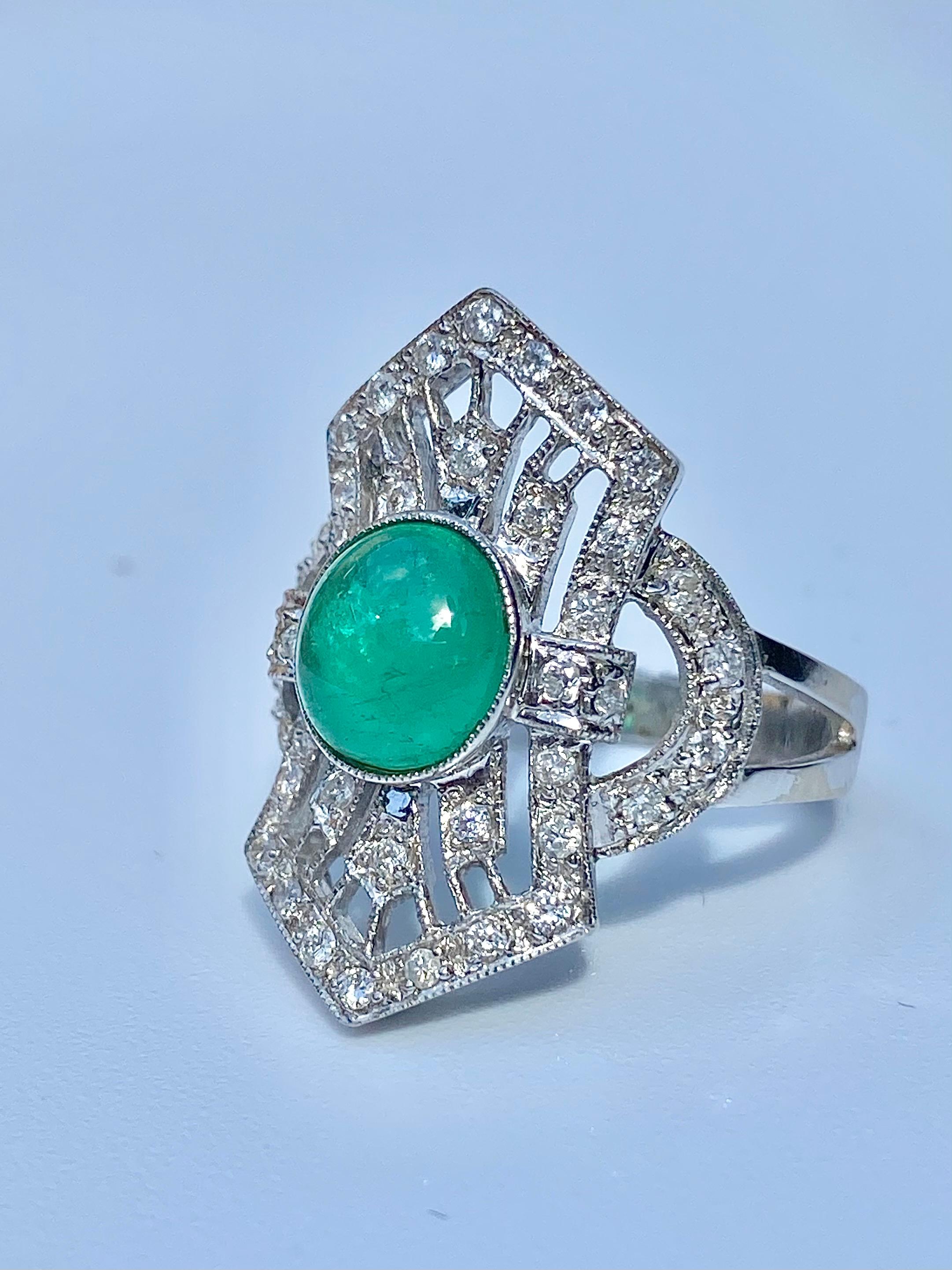 Centering a Cabochon-Cut 1.40 Carat Green Colombian Emerald, accented by an additional 0.66 Carats of Round-Brilliant Cut Diamonds, and set in 14K White Gold, this vintage classic is a tribute to a bygone era of jewelry craftsmanship. 

Ring