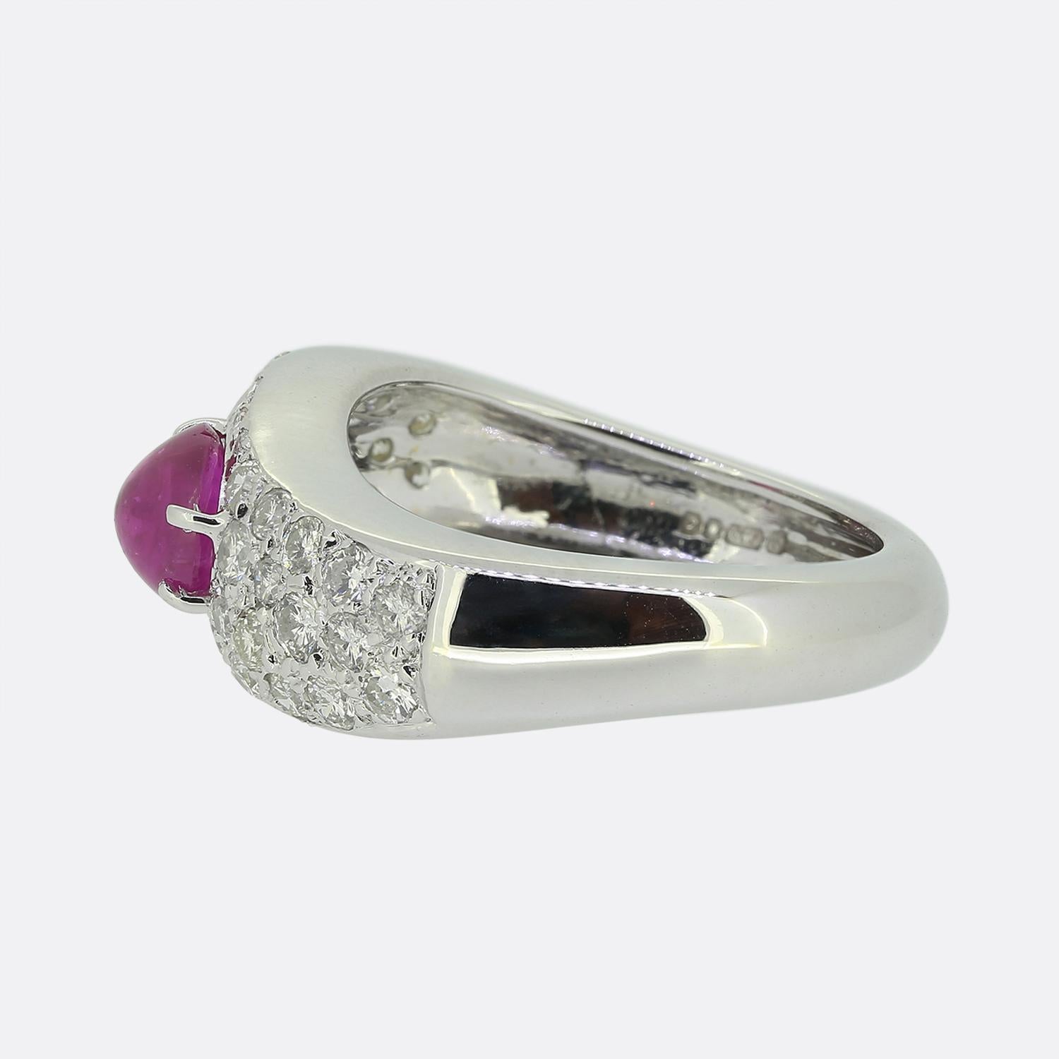 Dies ist ein Ring aus 18 Karat Weißgold mit Rubinen und Diamanten. Er zeigt einen einzelnen ovalen Rubin in Cabochonform, der von runden Diamanten im Brillantschliff umgeben ist, die in einer Weißgoldfassung im Twist-Stil gefasst sind.

Zustand: