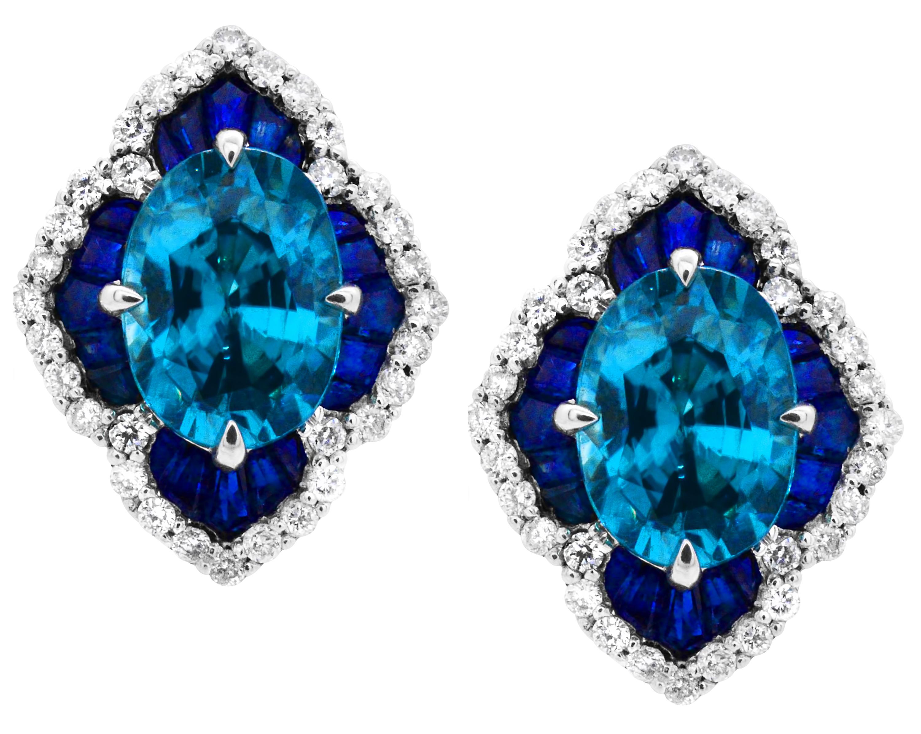 Bright Blue Zircon Scalloped 14Karat White Gold Stud Earrings.  The center 7 x 5 mm 1.40 carat oval Blue Zircon on these earrings will delight you with their cool crisp color.  The 3.20 carats of accompanying handset tapered baguette sapphires will