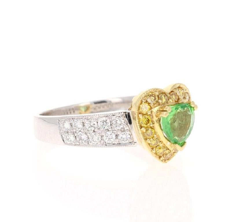 The heart shaped Tsavorite weighs 0.77 Carats and is surrounded by natural Yellow Diamonds that weigh 0.25 Carats, there are also 20 Round Cut Diamonds that weigh 0.38 Carats. The total carat weight of the ring is 1.40 Carats. The heart cut