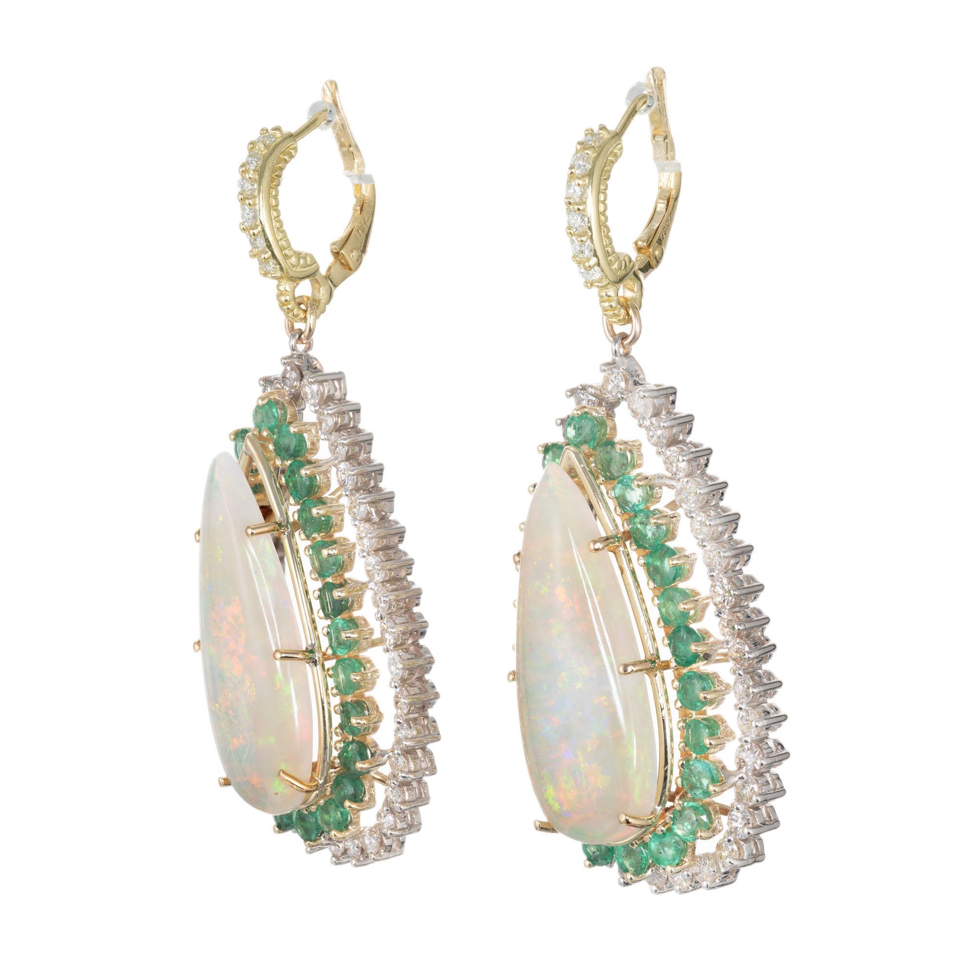 1960’s opal dangle earrings. Two pear shape 14.00ct opals with orange, green and blue flash. 48 round cut emeralds and 70 round cut diamond halos. Set in 14k yellow and white gold with 12 round brilliant cut accent diamonds along the hoops. 

2 pear