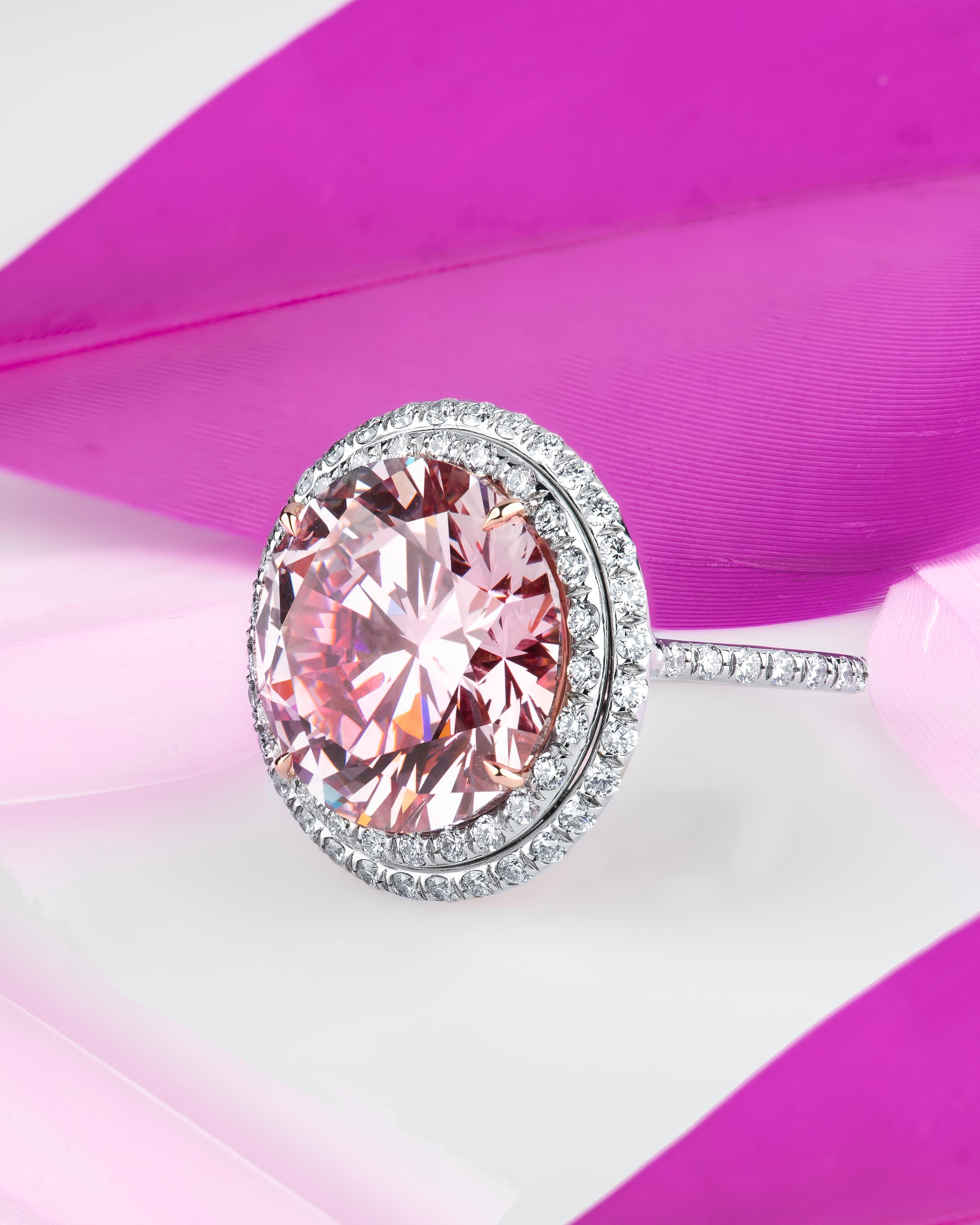 Beautiful 14.00 carat round brilliant cut pink diamond set in a custom platinum ring with approximately 2.15ctw in fine white diamonds with a custom rose gold gallery. The center diamond is of natural origin and has been treated through the process