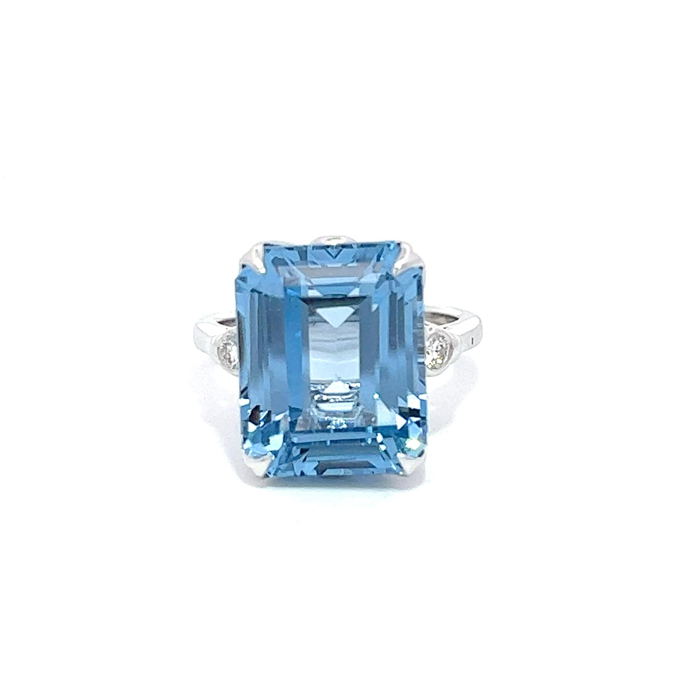 Dieser exquisite Verlobungsring besticht durch einen bemerkenswerten 13,50 Karat Blautopas, der elegant in 14 Karat Weißgold gefasst ist. Zwei runde Brillanten schmücken jede Seite des Steins und tragen zu seiner atemberaubenden Schönheit bei. Es