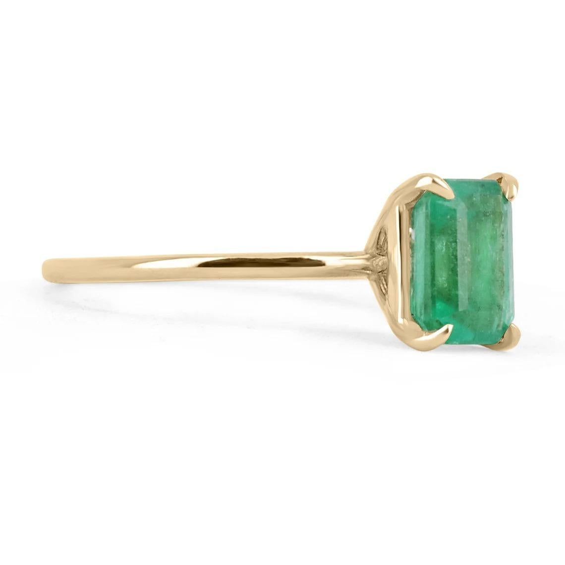Displayed is a custom emerald solitaire emerald-cut ring in 14K yellow gold. This gorgeous solitaire ring carries a 1.40-carat emerald in a four-prong setting. The emerald has very good clarity with minor flaws that are normal in all genuine