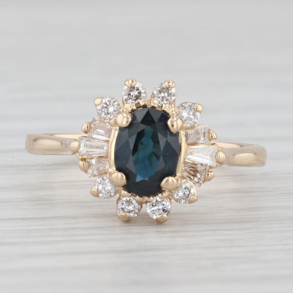 Gemstone Information:
- Natural Sapphire -
Carats - 1ct 
Cut - Oval
Color - Dark Blue
Treatment - Heated

- Natural Diamonds -
Total Carats - 0.40ctw
Cut - Round Brilliant 0.20ctw, Baguette 0.20ctw
Color - G - H
Clarity - SI2 - I1

Metal: 14k Yellow