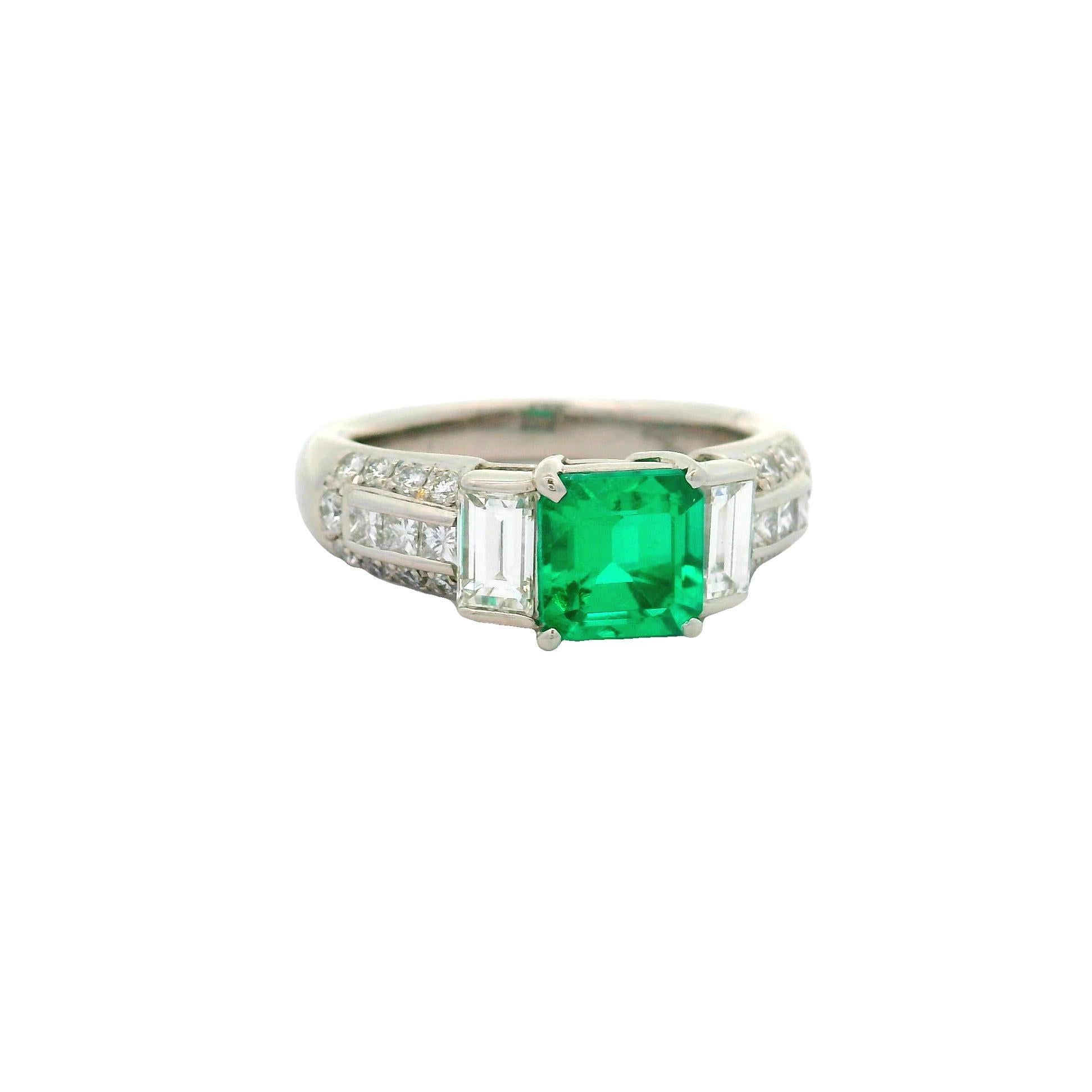 A captivating emerald, weighing 1.41 carats, commands attention at the center of this elegant ring. The emerald-cut stone radiates a vivid green hue, drawing the eye with its rich color and clarity. Flanking the central gem are two baguette-cut