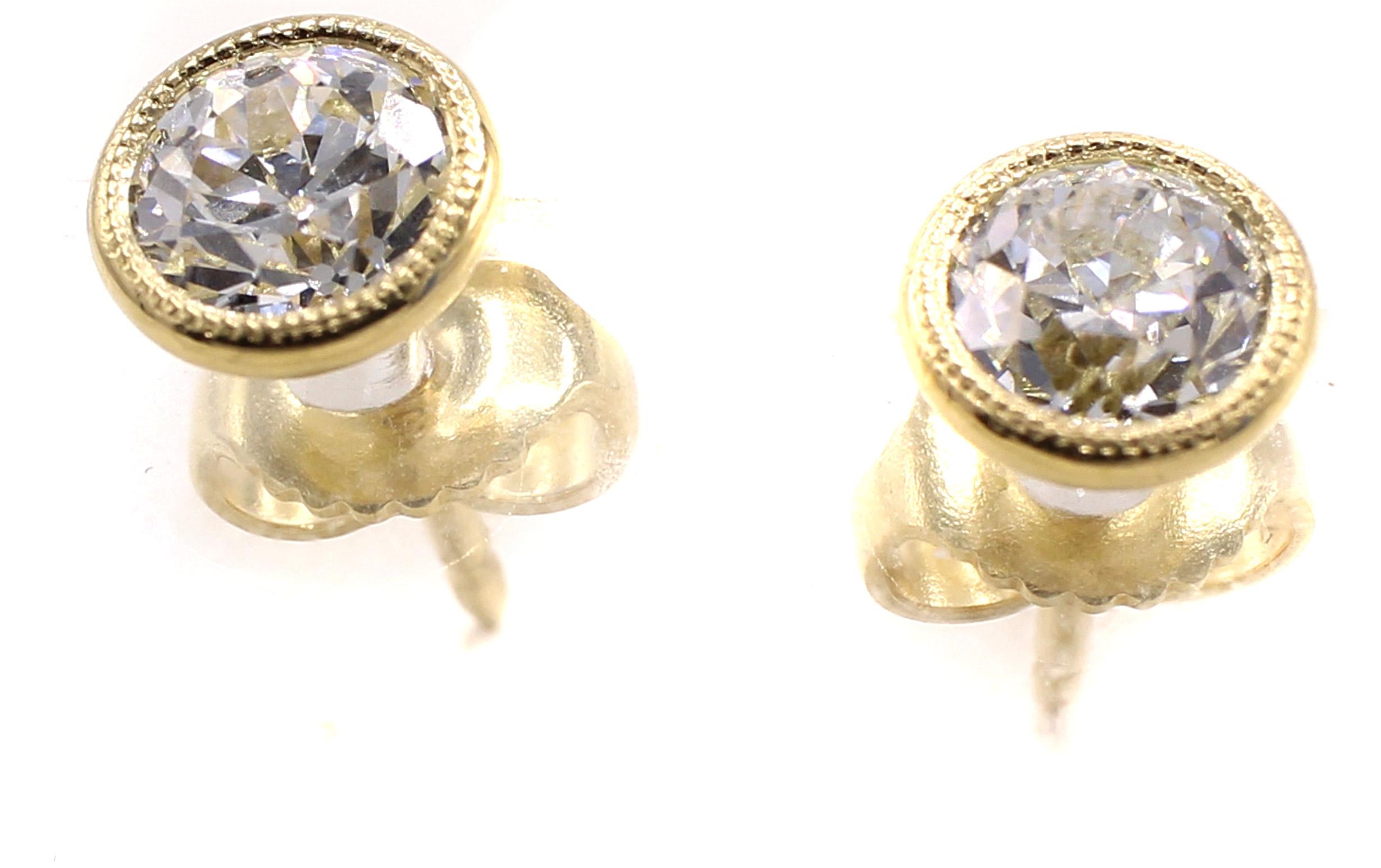 Two charming Old European Cut diamonds with a total weight of 1.41 carats have been set into these handcrafted 18 karat white gold bezel set mountings. The tops of the bezels have fine milligrain work combining the new world with the old cuts from a