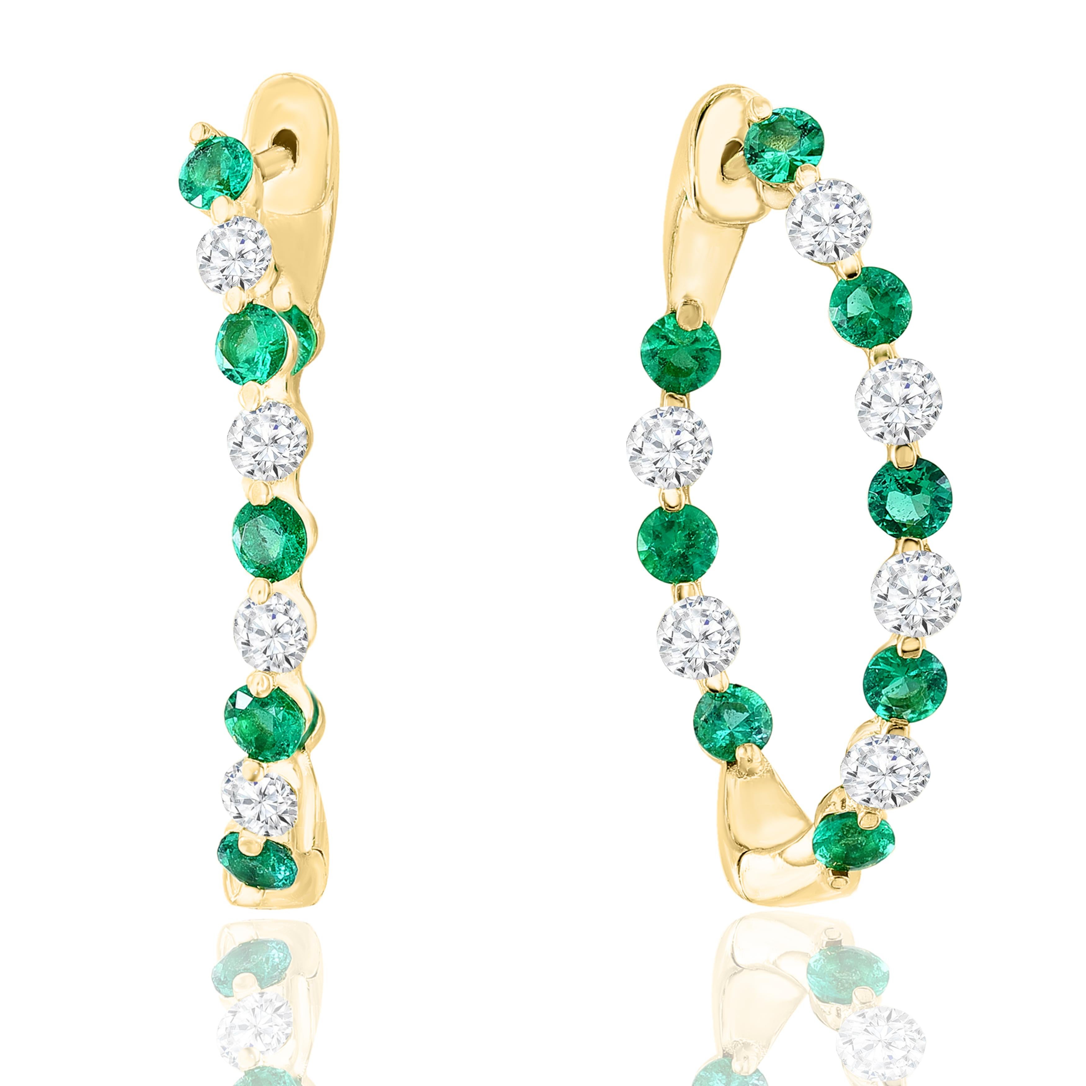 A chic and fashionable pair of hoop earrings showcasing brilliant-cut 16-round Emeralds alternating with diamonds, set in 14k yellow gold. 12 Round diamonds weigh 1.15 carats, and 16 Blue Sapphires weigh 1.41 carats. A beautiful piece of