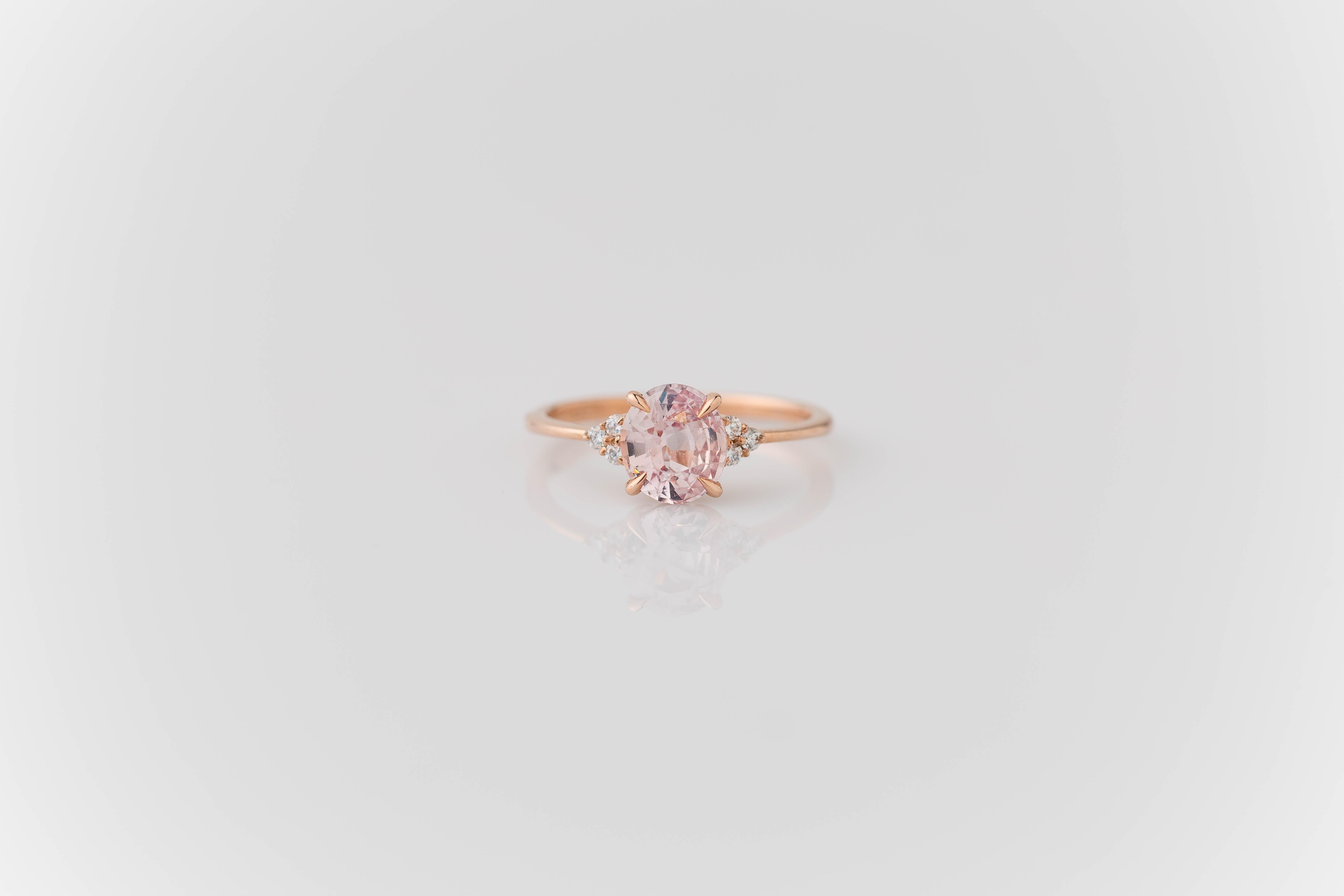 This elegant 14K rose gold knife-edge style ring features a stunning and unheated 1.41-carat oval peachy-pink sapphire at its center, certified by the GIA for its quality and authenticity. Flanking the sapphire are six round brilliant cut diamonds,