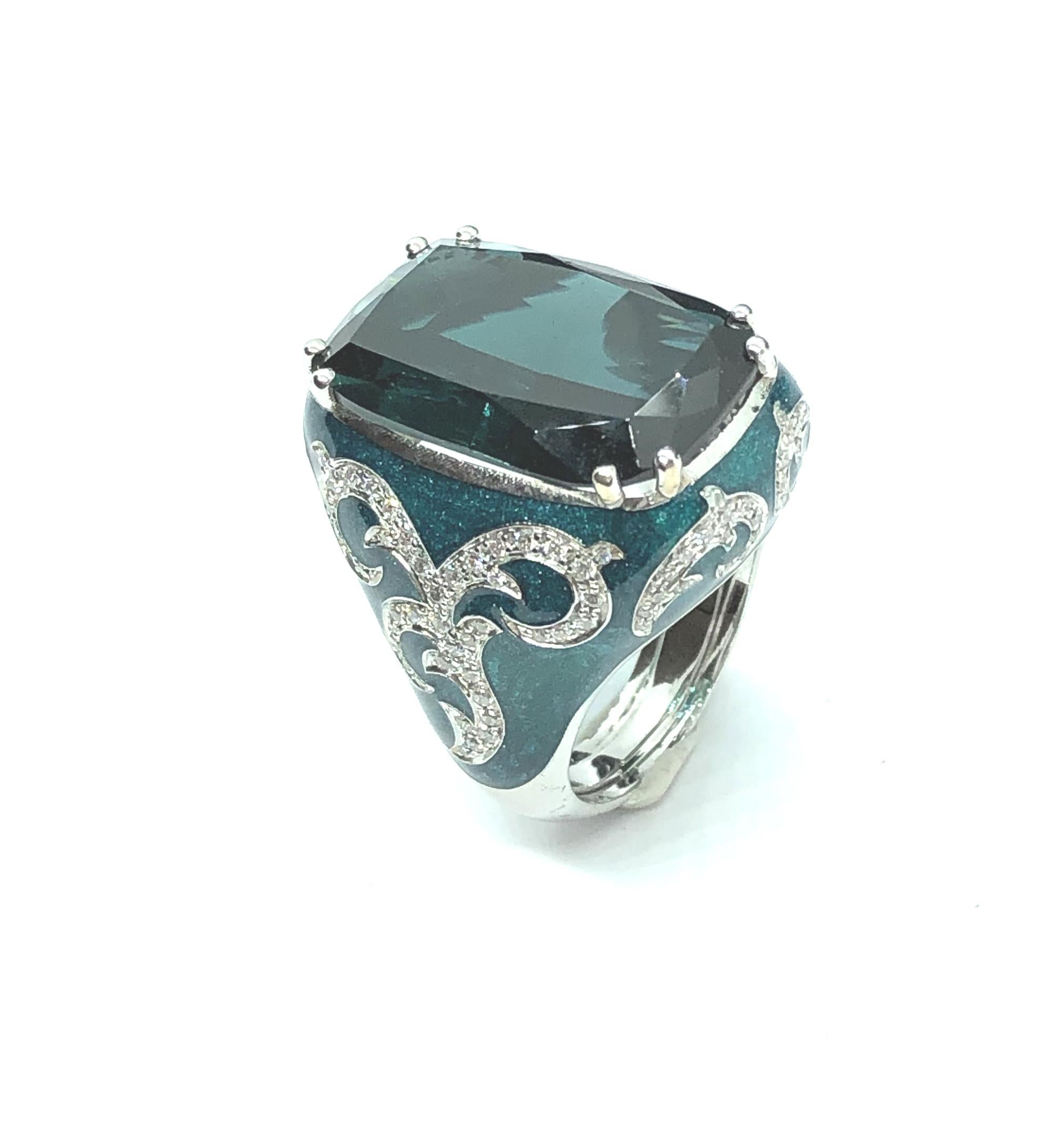 An Exclusive Enamel Cocktail ring Ring in 18 Kt White Gold, setted with 0,72 cts of brilliant cut VS quality  with a rare cushion cut Indicolite Tourmaline Blue Green of 14,12 carats loope clean that measures 20,8 x 13 mm.

This ring is designed and