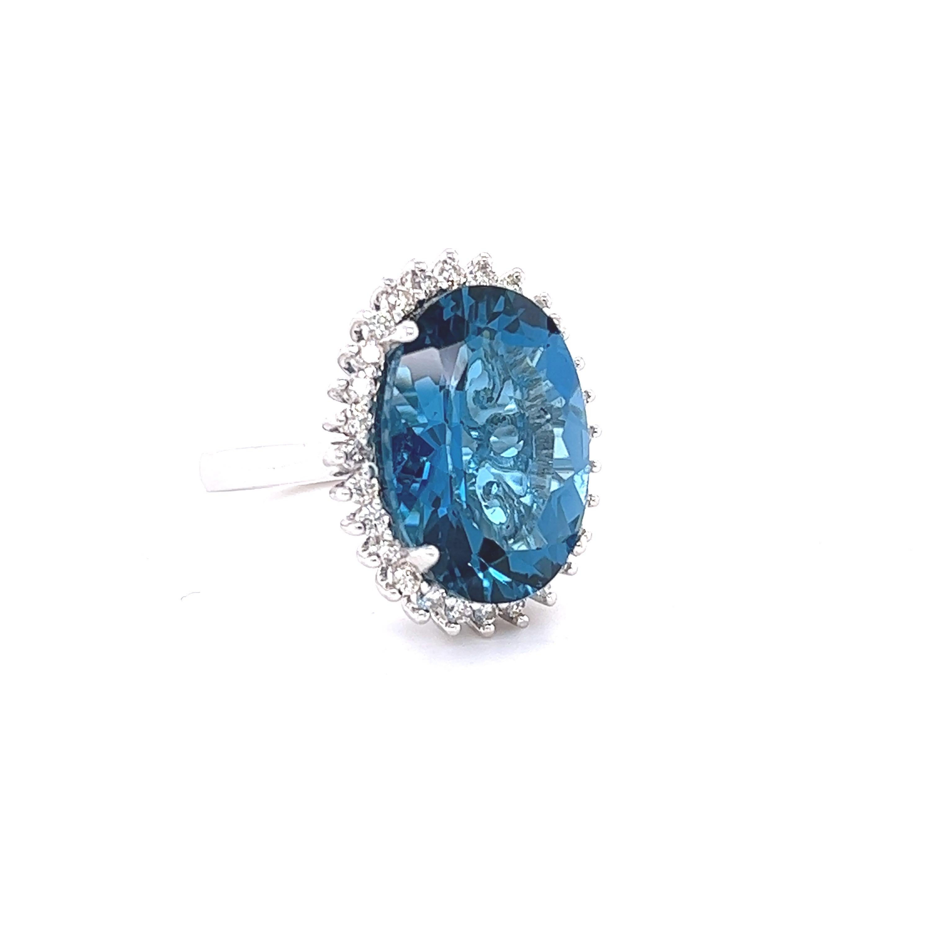 This stunning statement ring has a large Oval Cut Blue Topaz that weighs 13.62 Carats. 
It is surrounded by a simple halo of 28 Round Cut Diamonds that weigh 0.57 Carats. (Clarity: VS, Color: H)

It is crafted in 14 Karat White Gold and weighs