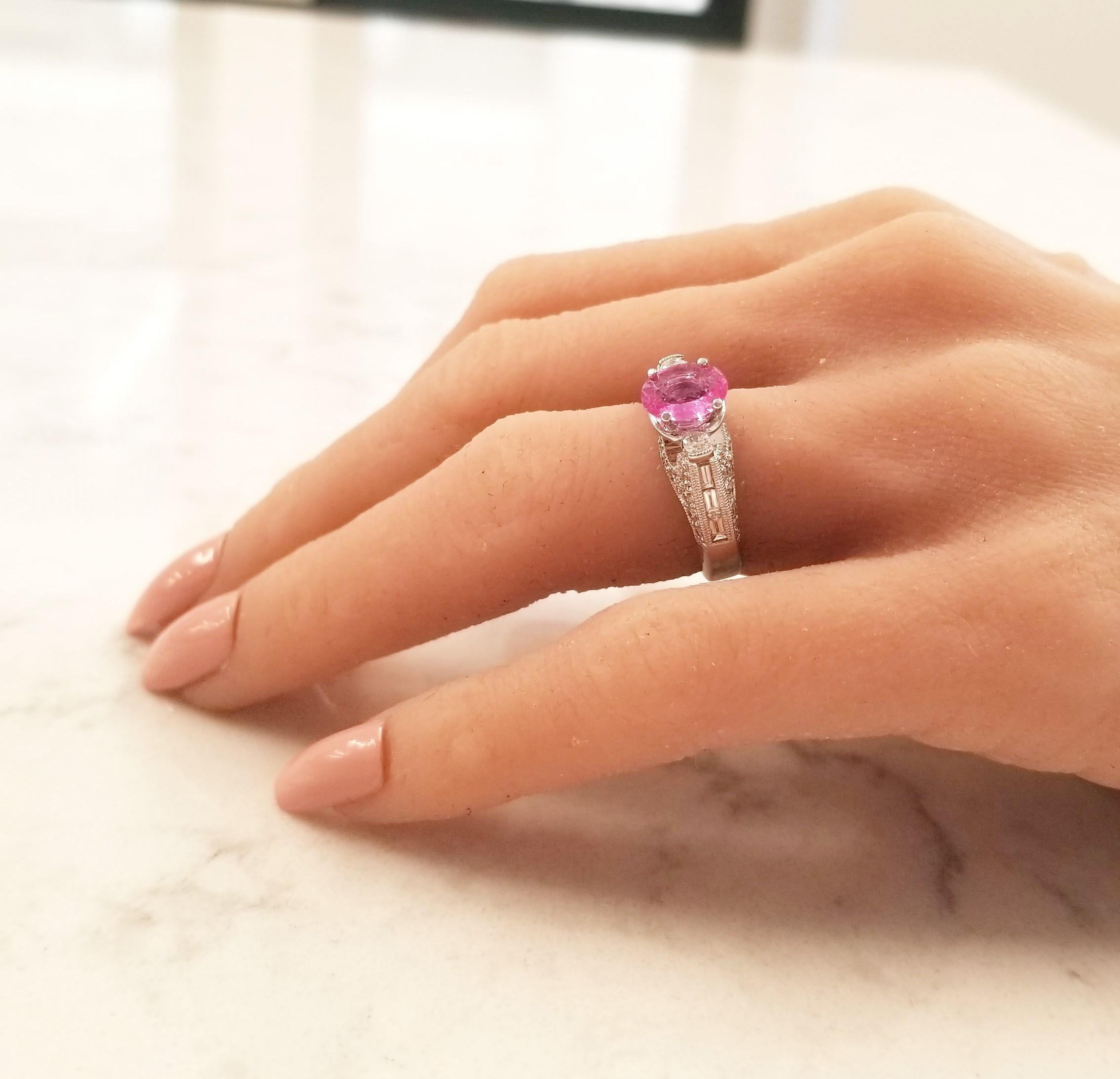 This ring is guaranteed to sparkle, and it captivates from every angle. You’ll never tire of looking at all the stunning details that make this piece a delight to behold. The ring features a 1.42ct oval vivid pink sapphire that sits in the center of