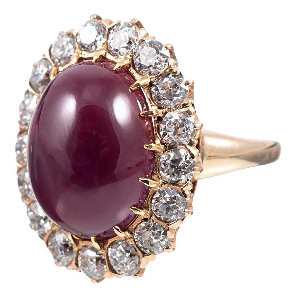This charming cluster ring is set in the center with a 14.20 carat cabochon ruby and framed in a border of brilliant white diamonds. The 14 karat rose gold mounting offers a soft hue, which is quite symbiotic with the color of the major center
