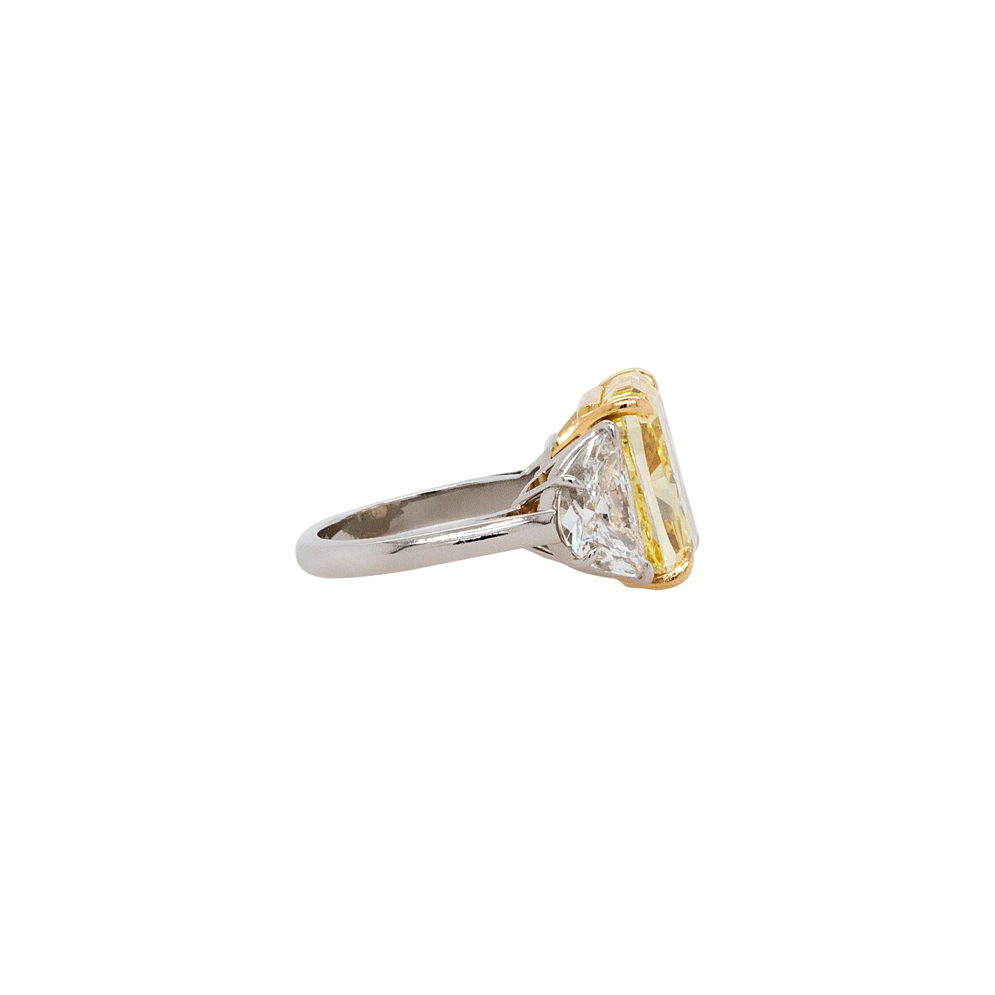 This ring features a stunning combination of platinum and 18k yellow gold, creating a luxurious and timeless design. The centerpiece of the ring is a magnificent 14.21-carat natural fancy vivid yellow color diamond, known for its exceptionally