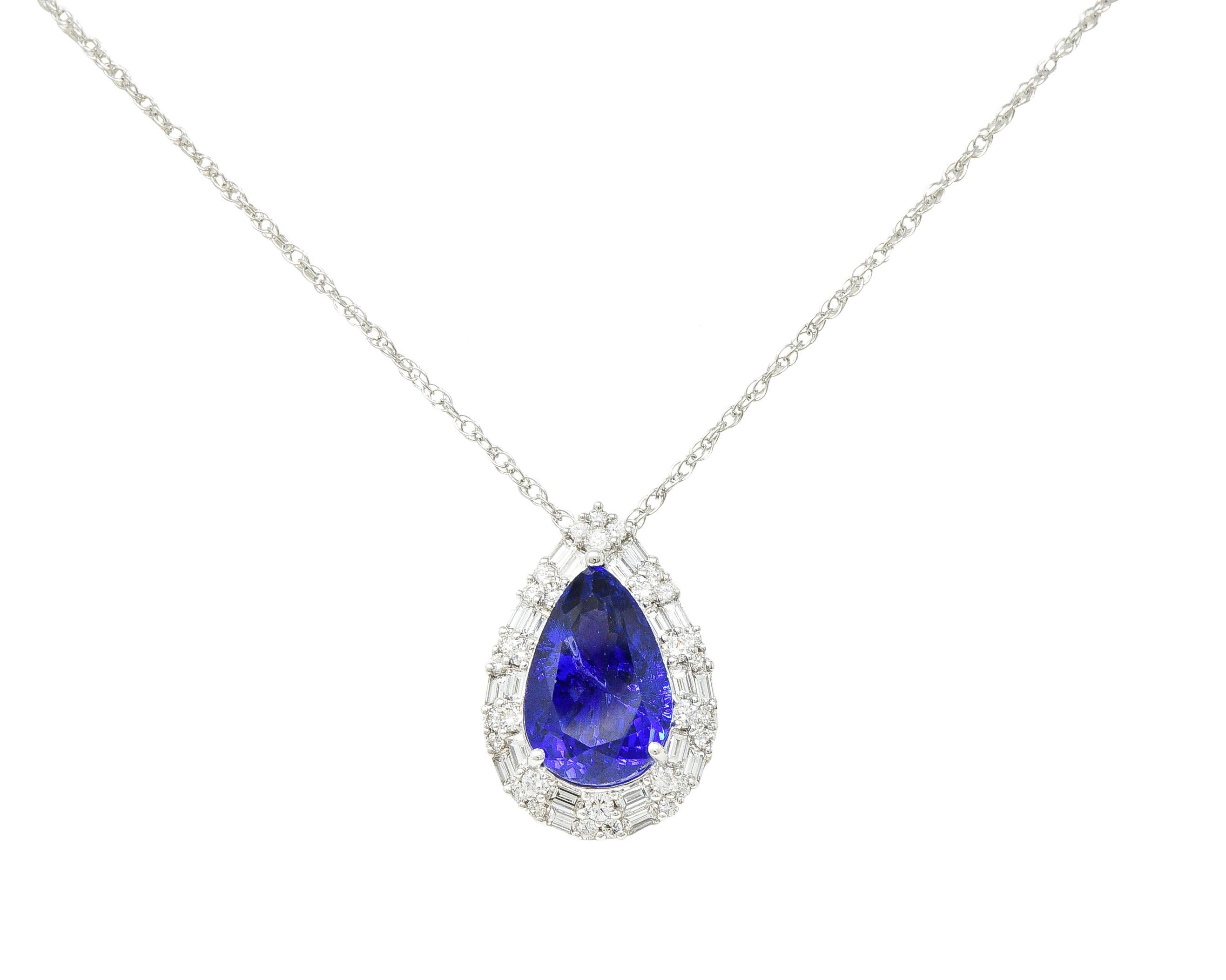 Centering a pear cut tanzanite weighing 11.57 carats total - prong set. Semi-transparent violetish-blue with natural inclusions. With a double halo surround and cathedral shoulders. Accented by round brilliant and baguette cut diamonds. Weighing