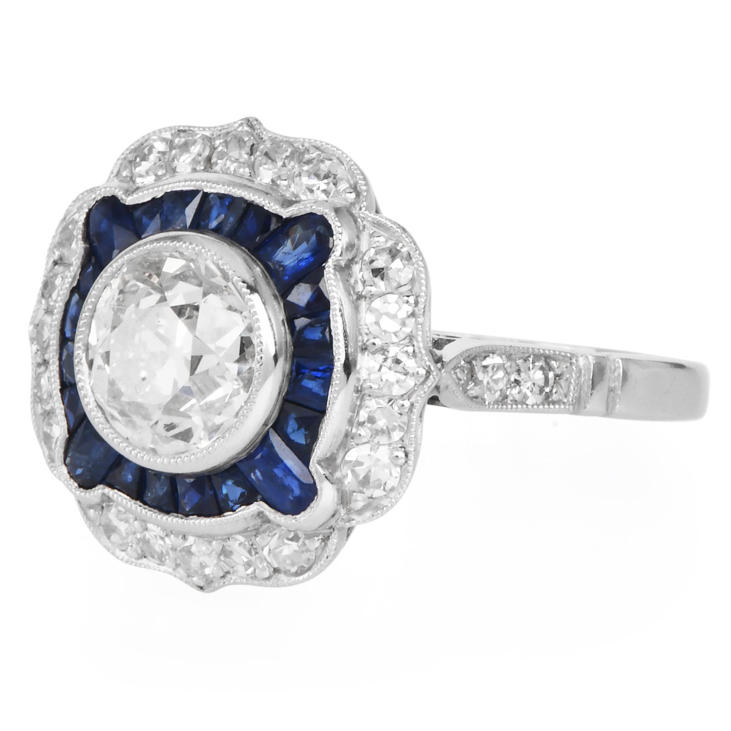 Il design richiama l'eleganza dell'epoca Art Deco. Con un diamante antico di taglio europeo al centro, incorniciato da un'aureola geometrica di zaffiri blu intenso tagliati con precisione e da un anello esterno di brillanti rotondi, questo pezzo è