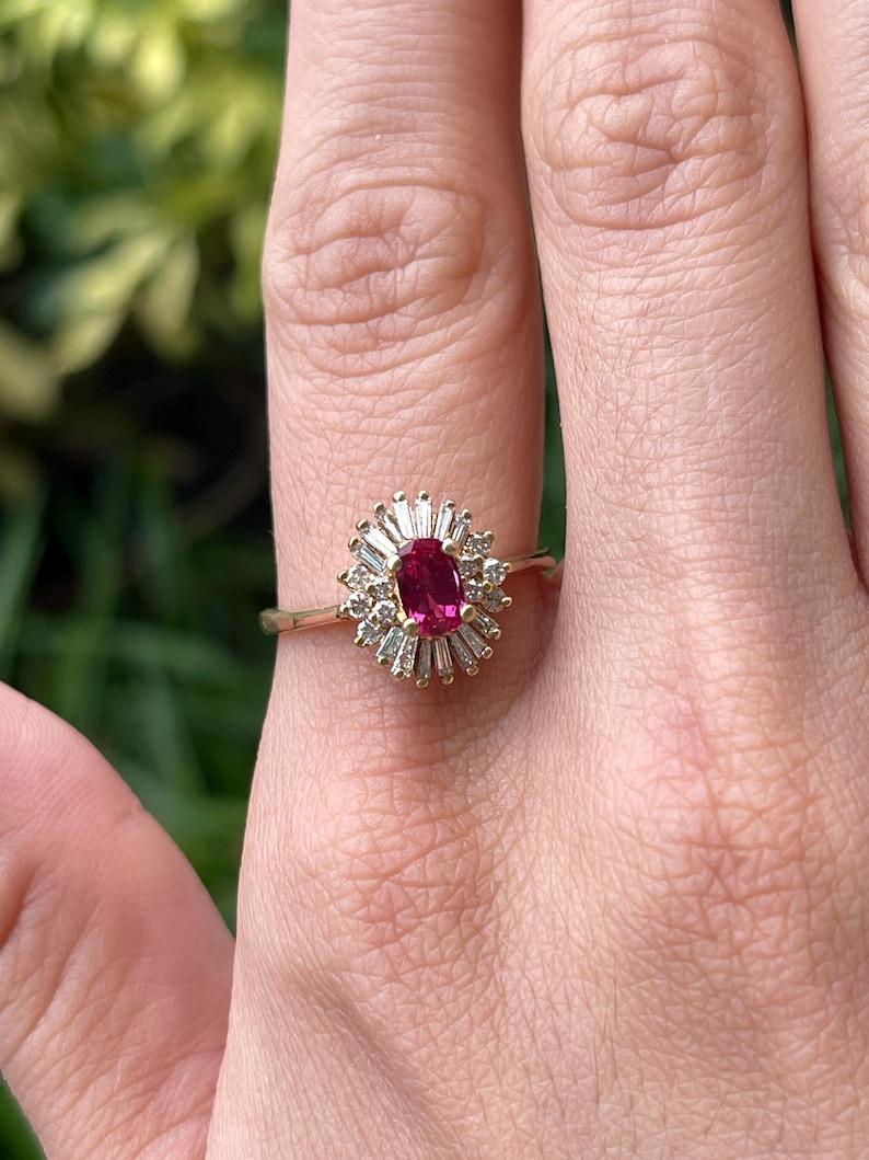 This exquisite ballerina ring showcases a breathtaking cushion-oval natural rubellite tourmaline, elegantly set in four prongs. Surrounding the vibrant center stone is a dazzling halo of tapered baguettes and round-cut diamonds, creating the classic