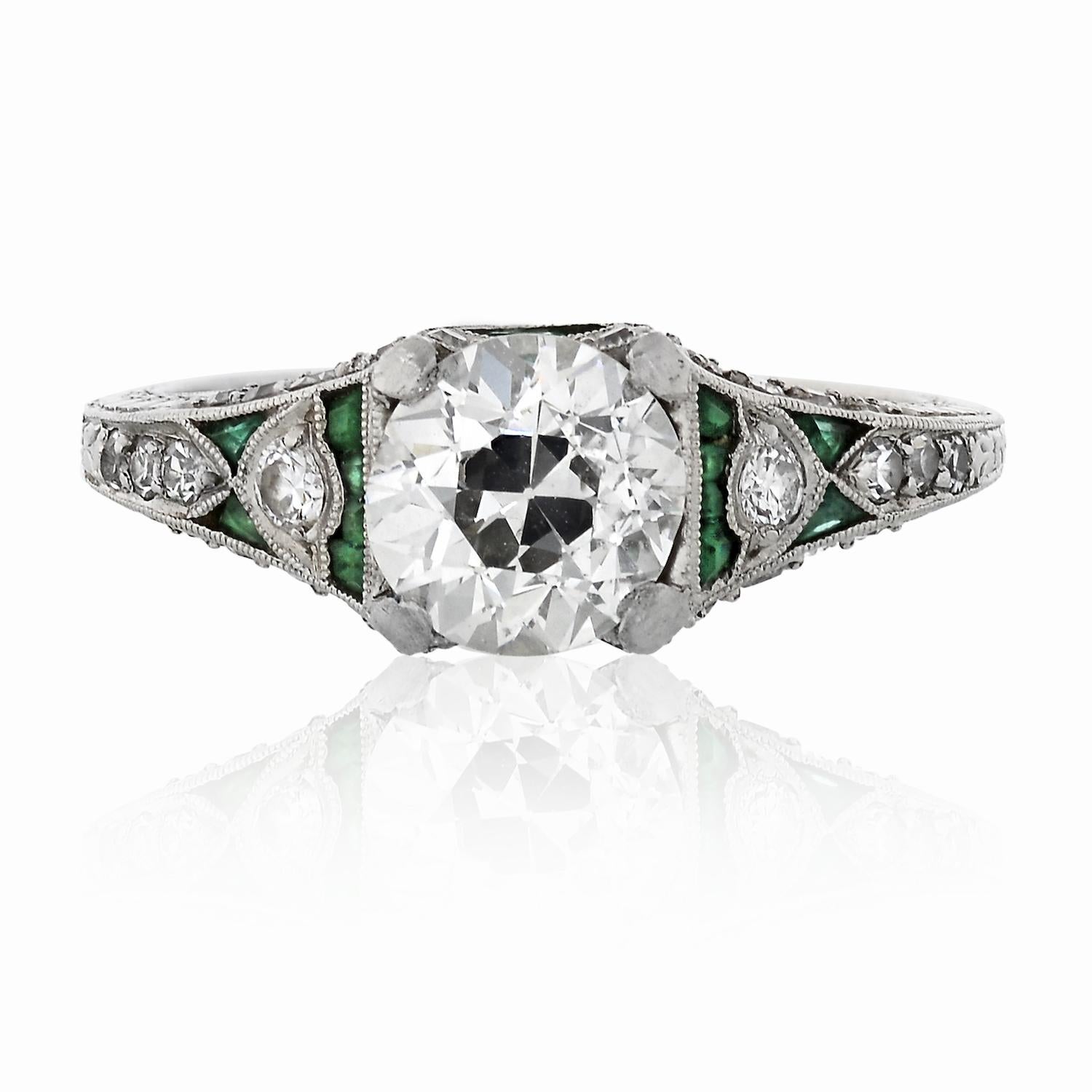 This original vintage circular-cut diamond filigree engagement ring features a 1.43 carat center stone accented by round cut diamonds and mixed shaped green emeralds. The Center diamond is a GIA certified circular-cut diamond of I color and SI2