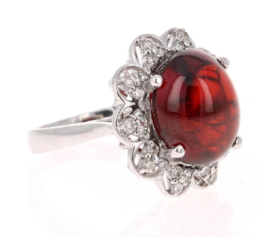 
This breath taking ring has a 13.85 Carat Oval Cabochon Cut Spessartine Garnet. Spessartines are natural gemstones that are a member of the Garnet Family.

This ring is adorned with 30 Round Cut Diamonds that weigh 0.50 Carats. The clarity and
