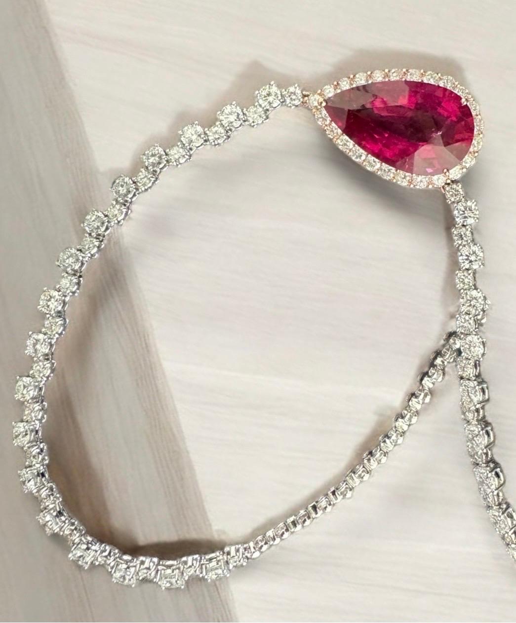 This exquisite necklace transforms the ordinary into the extraordinary. The rich, vibrant rubellite centre stone steals the spotlight, its pear-shaped facets refracting light to create mesmerising flashes of deep pink. Surrounded by a halo of
