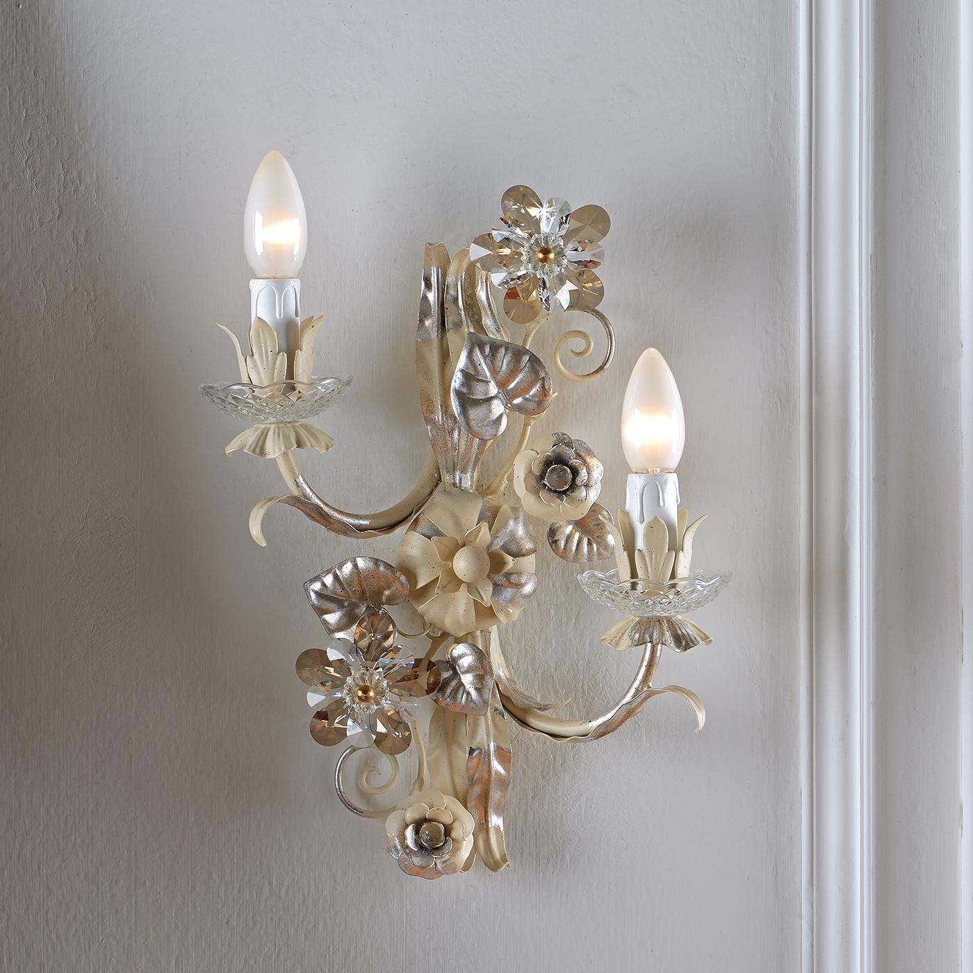 A charming applique, inspired by Italian tradition and nature. Made in metal, the applique is coated with a ivory finish and accented with silver leaf. Completing the applique are Asfour crystal flowers, in transparent and smoky tones. Perfect for