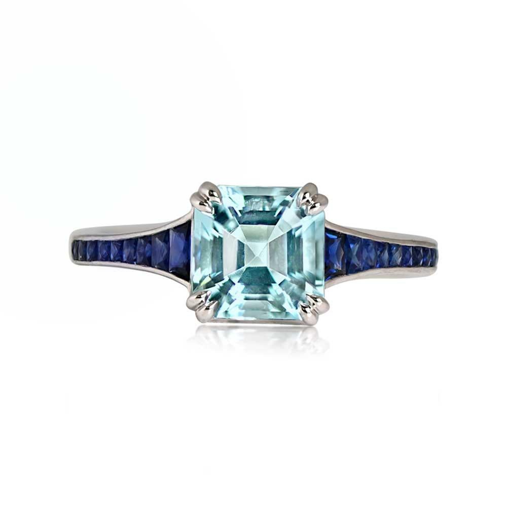 A captivating platinum ring with a 1.43-carat Asscher-cut aquamarine, secured by double prongs. The tapered shoulders feature channel-set calibre French-cut sapphires, continuing down the shank. The under-gallery is intricately adorned with