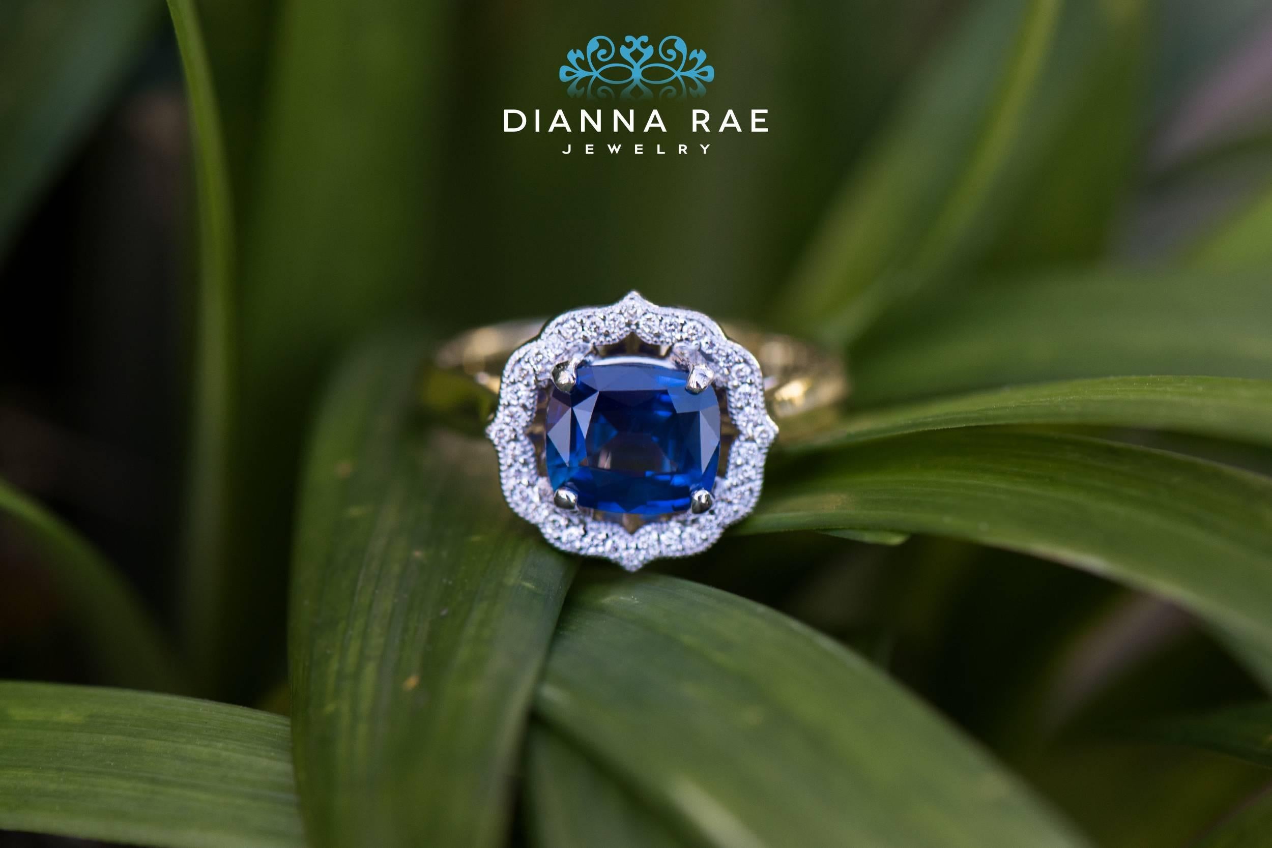 This gorgeous Rae-Halo Sapphire ring features a 1.44 carat cushion cut natural blue sapphire. There are 36 bright SI2 quality GH color diamonds brilliantly sparkling in a beautifully designed halo. This vintage and floral inspired ring is truly an