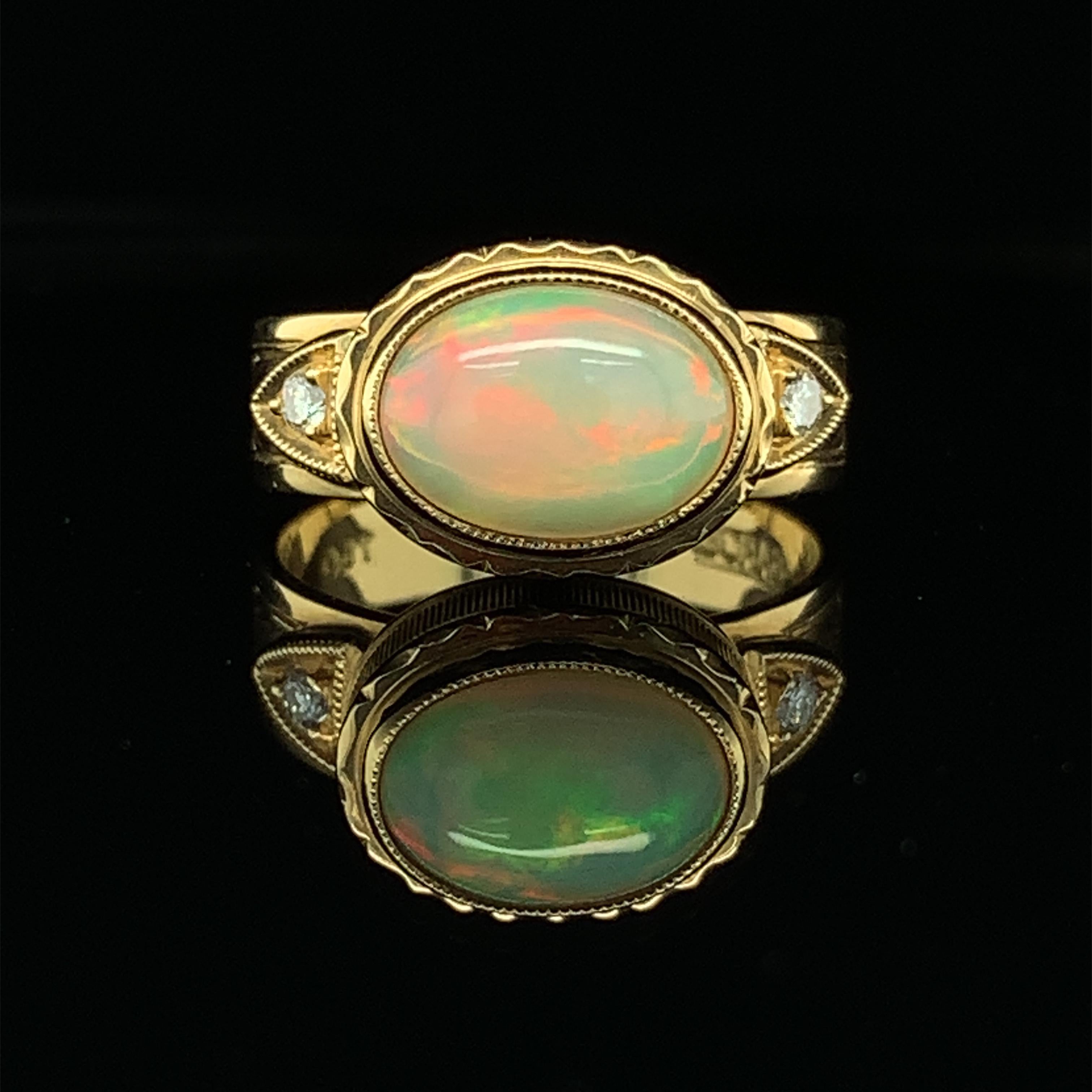 This ring is a brilliantly bright delight for your finger! A colorful 1.44 carat opal is bezel set with sparkly diamonds in an 18k yellow gold setting that is intricately and beautifully engraved. Guaranteed to brighten any day and put a smile on