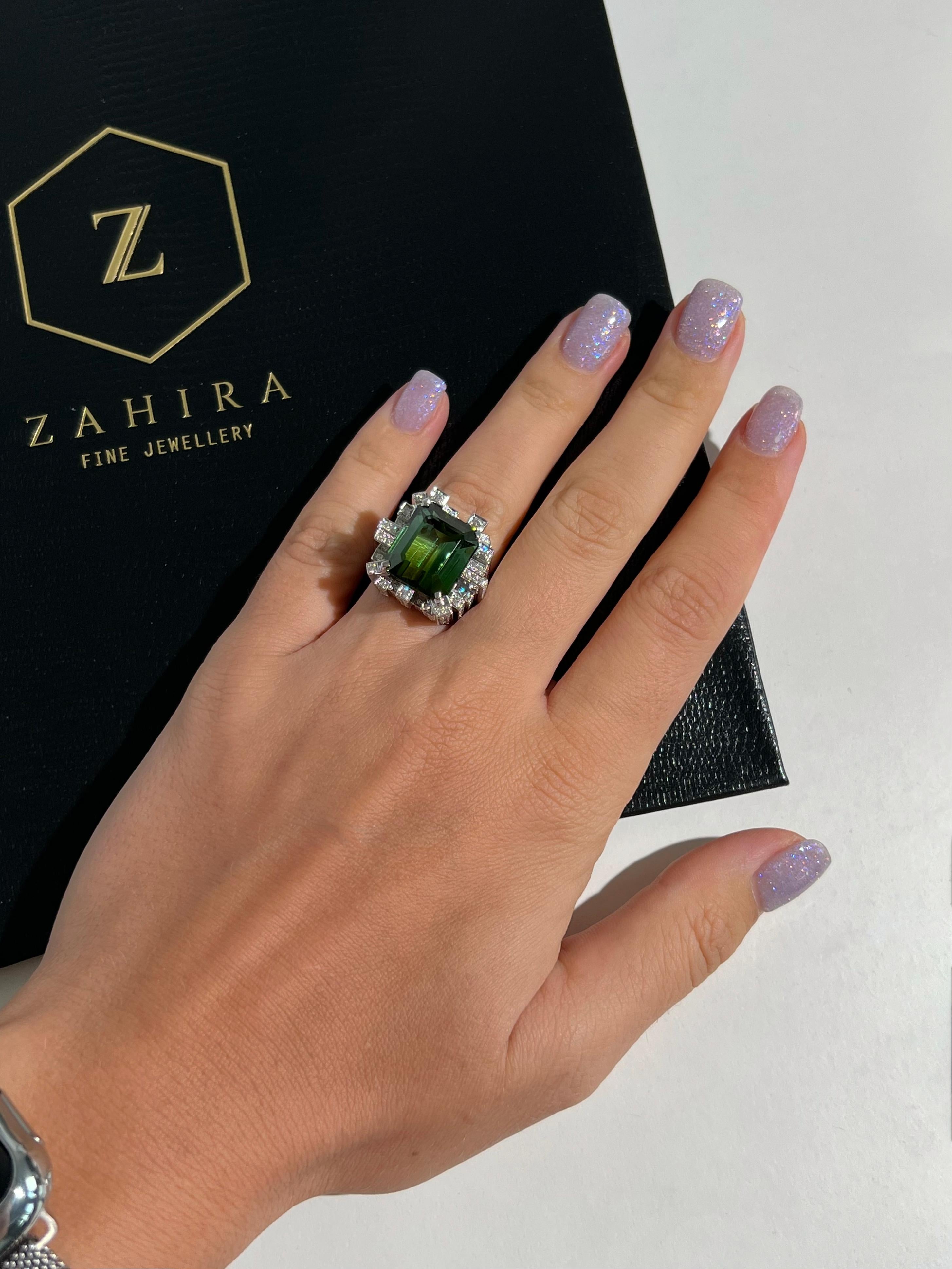 A 14.49 ct bi color green tourmaline is the center stone of this ring. Beautiful shades of green cascade down this emerald cut stone. Natural and eye clean, this bi color tourmaline is accented with 2.07 cts of natural G VS diamond towers set in 18k