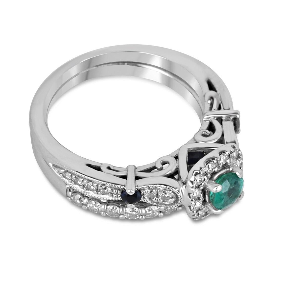 Celebrate an everlasting love with this exquisite emerald, diamond, and blue sapphire engagement ring. Nestled at the heart of the design is a medium lush green emerald with a captivating bluish tint, meticulously cut to enhance its brilliance,