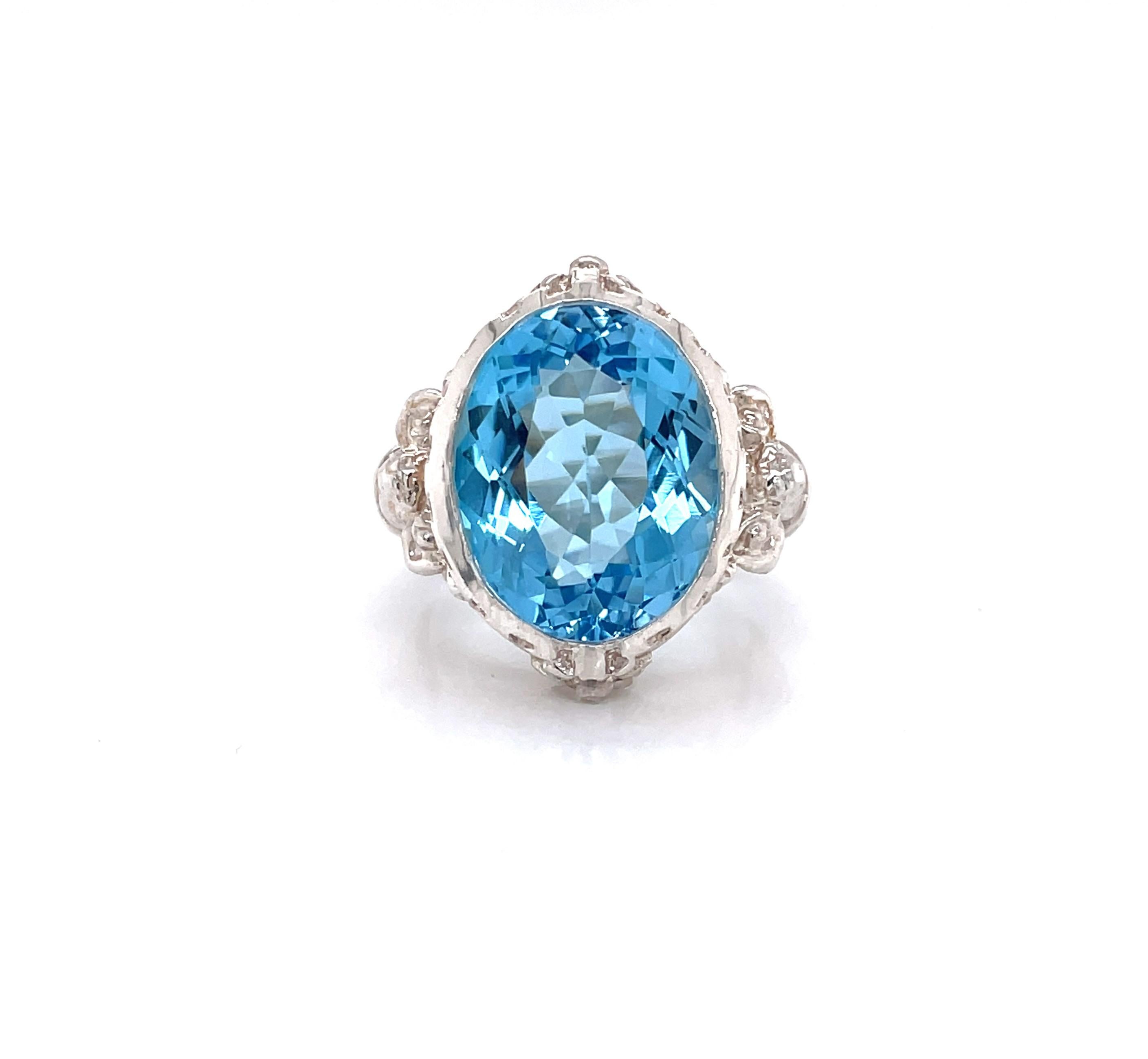 A stunning 14.5 carat oval faceted vivid blue topaz is the star of the show in this unique and ornate sterling silver cocktail ring. This is the prototype piece made in silver for an original ring design commissioned by world famous actress