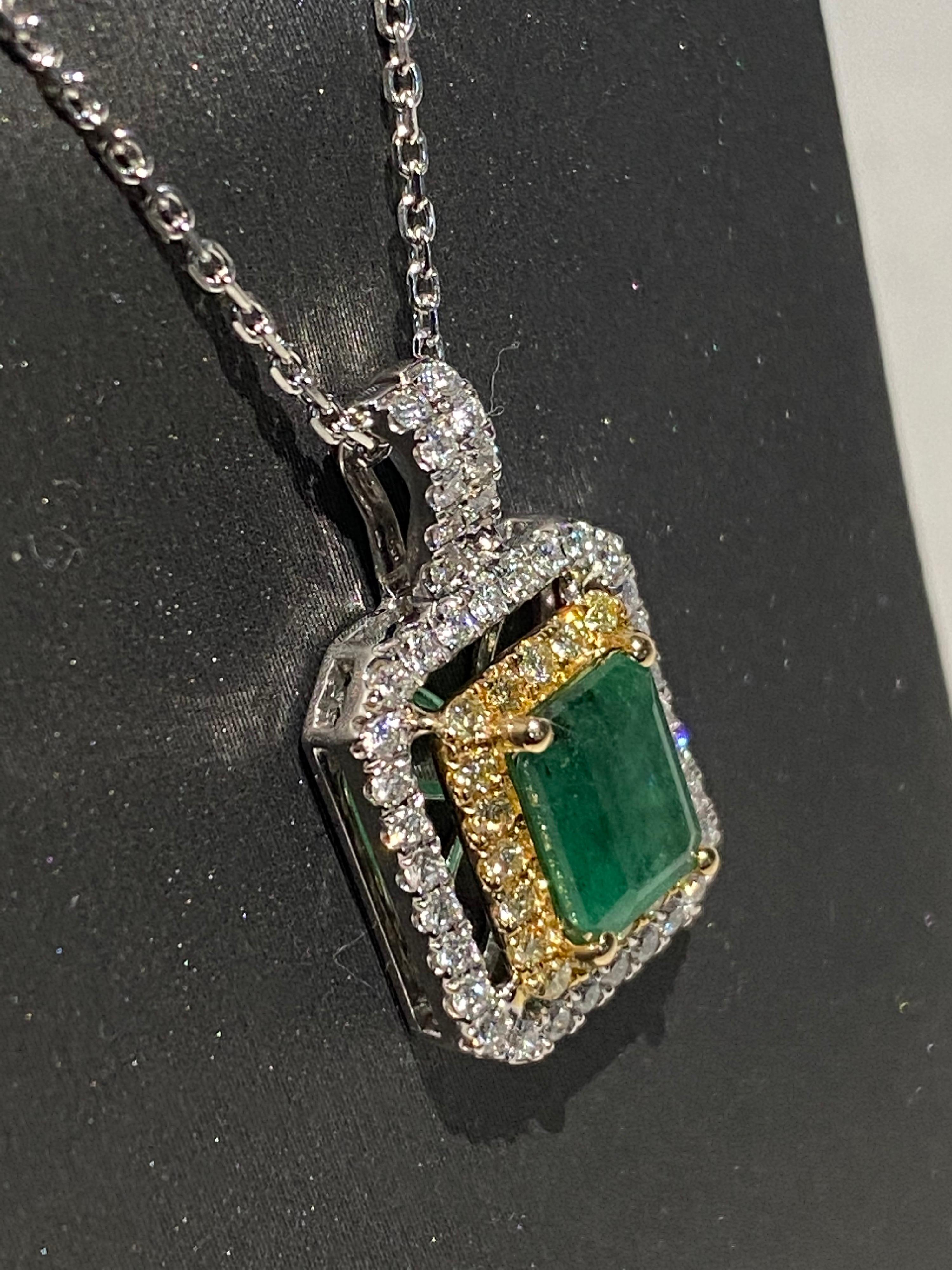 Emerald cut emerald has double halo of yellow and white diamonds. Double halo makes the center stone stand out and look bigger. Set in two tone gold, a white gold chain is included. 
Emerald: 1.45ct
White Diamond: 0.40ct
Yellow Diamond: 0.22ct
Two