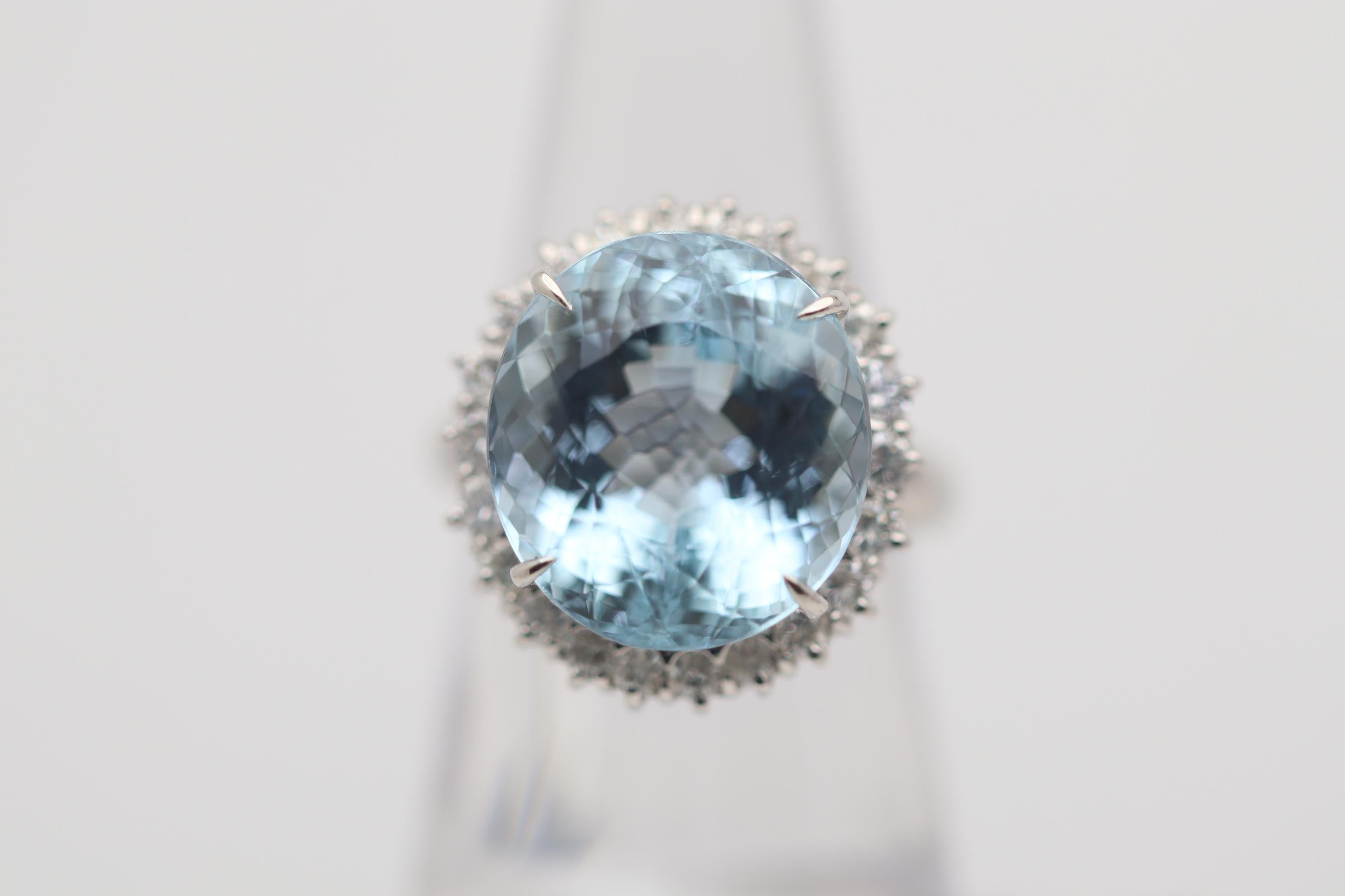 A stunning aquamarine with the ideal rich sea-blue color takes center stage. It weighs an impressive 14.52 carats and has a special cut (Portuguese-cut) which increases the stone's brilliance and sparkle. It is complemented by a halo of round