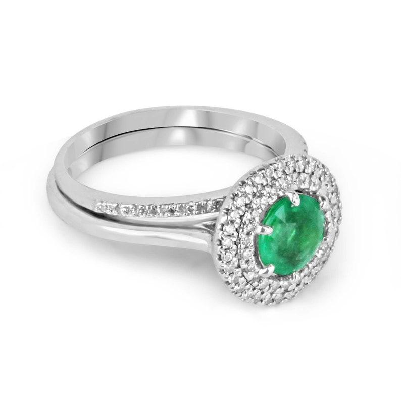 This stunning ring showcases a vivacious 1.10-carat round-cut emerald as its centerpiece, featuring a unique and eye-catching yellowish-green hue with distinctive characteristics. The emerald is set in a six-prong mount, ensuring maximum visibility