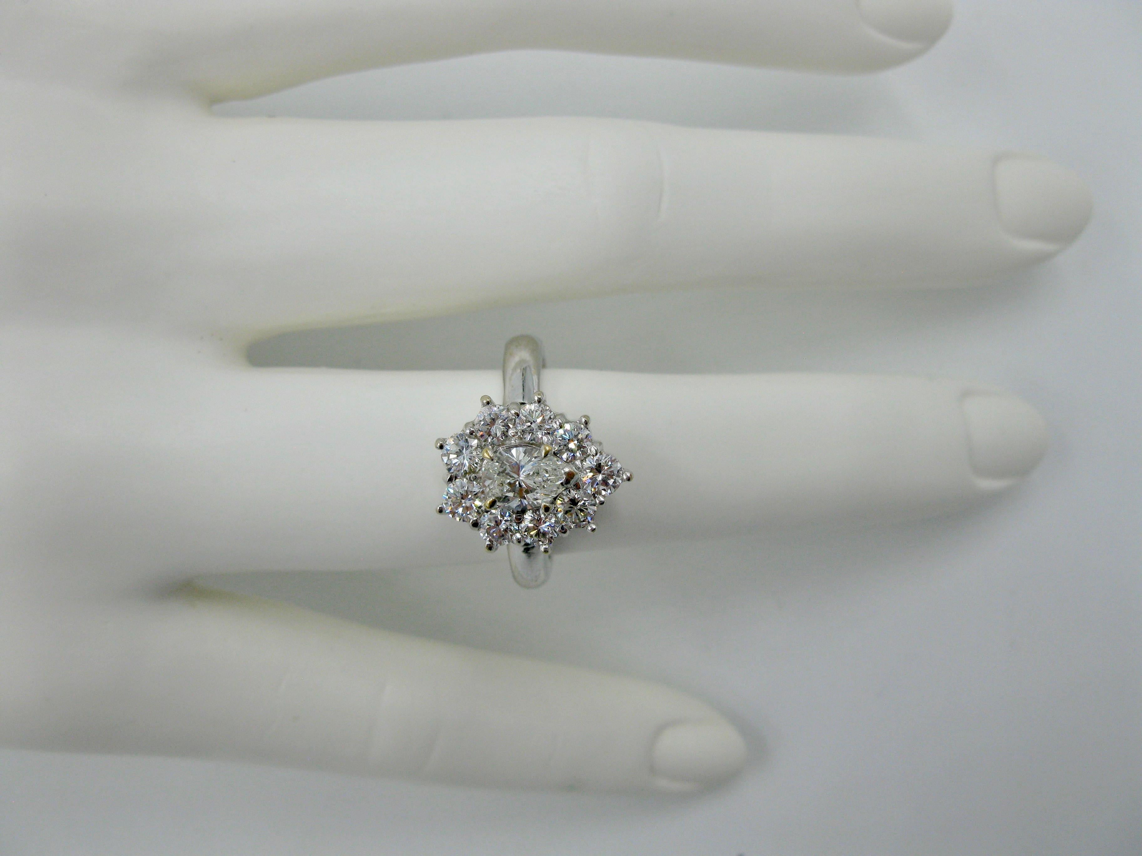 A dramatic Diamond Wedding Engagement Ring or Cocktail Ring with a stunning central pear shape diamond of .56 Carat.  The diamond is a brilliant white, clean gem that is I color and VS clarity.  This stunner is surrounded by a halo of nine round