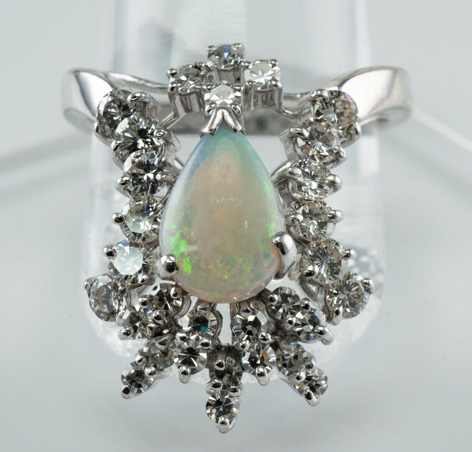 This estate ring is made in solid 14K White Gold and set with genuine Opal and diamonds.
The center Earth mined Pear Cut Opal measures 10mm x 7mm (1.03 carats). 
It has splashes of electric green, blue, orange colors! 
18 single cut diamonds (.72ct)