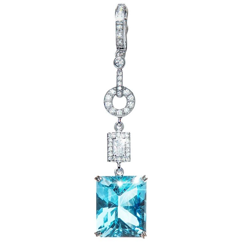 The star of this Blue Topaz and Diamond Enhancer is a natural Emerald Cut Blue Topaz weighing 14.66 carat. Its beauty is further enhanced by the contrast of 3 tier of diamonds, starting with a diamond enhancer, a pave set diamond circle section and