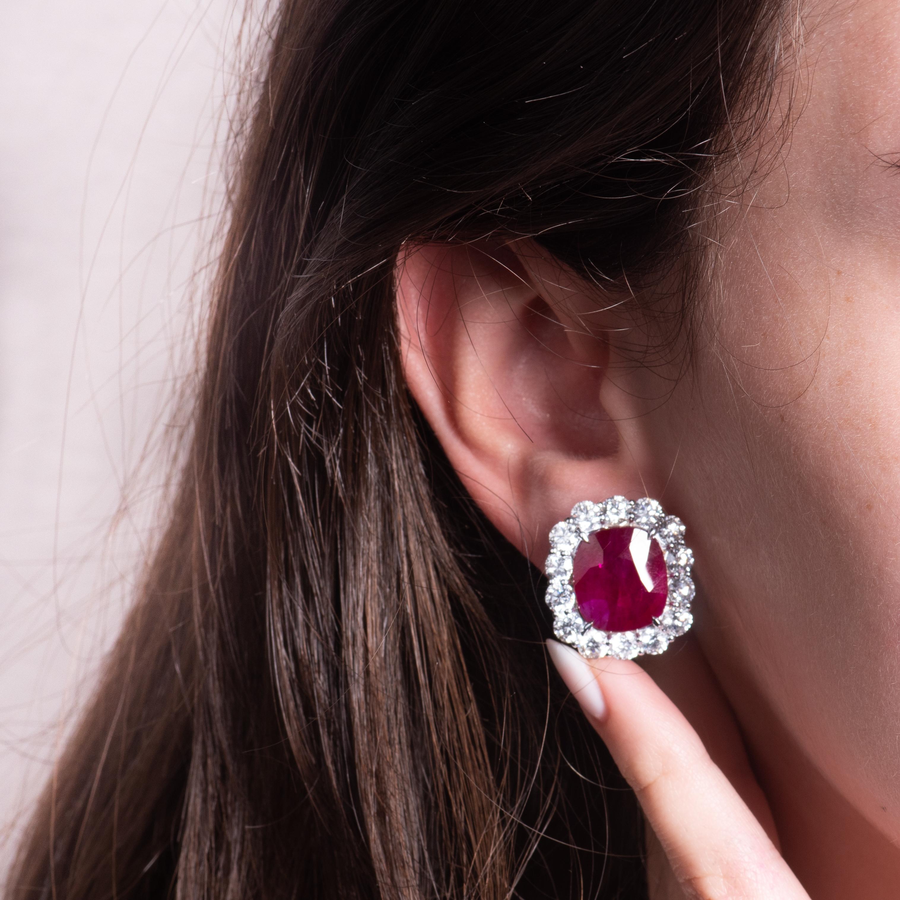 These incredible 14.73ct total weight cushion shape/mixed cut Mozambique rubies are an intense red color, surrounded by 6.93ct total weight in colorless round diamonds forming their halos. These precious gems are set in an 18kt white gold earrings,