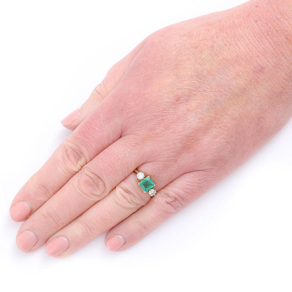 A pretty vintage 18 karat yellow gold 1.48ct emerald and 0.60ct diamond three stone ring. The emerald cut emerald is claw set with the two-round sparkling brilliant cut diamonds flanking the centre stone. A vintage ring dating from the the 1970's