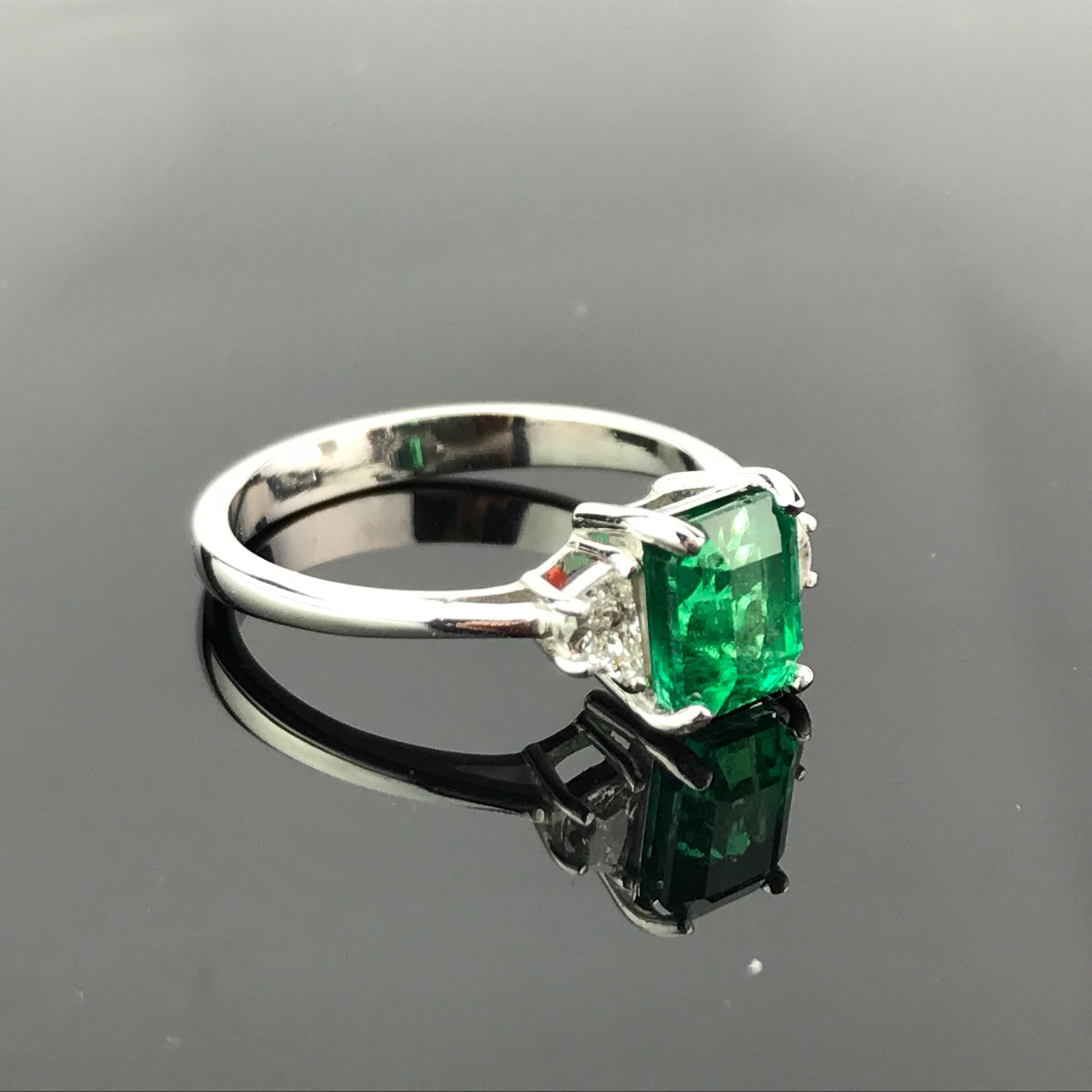A classic three stone ring, with a 1.48 carat high quality and great colour emerald cut Zambian Emerald centre stone, and 2 half-moon 0.24 carat side stone Diamonds all set in 3.32 grams of 18K White Gold. Currently a ring size US 6, but we can