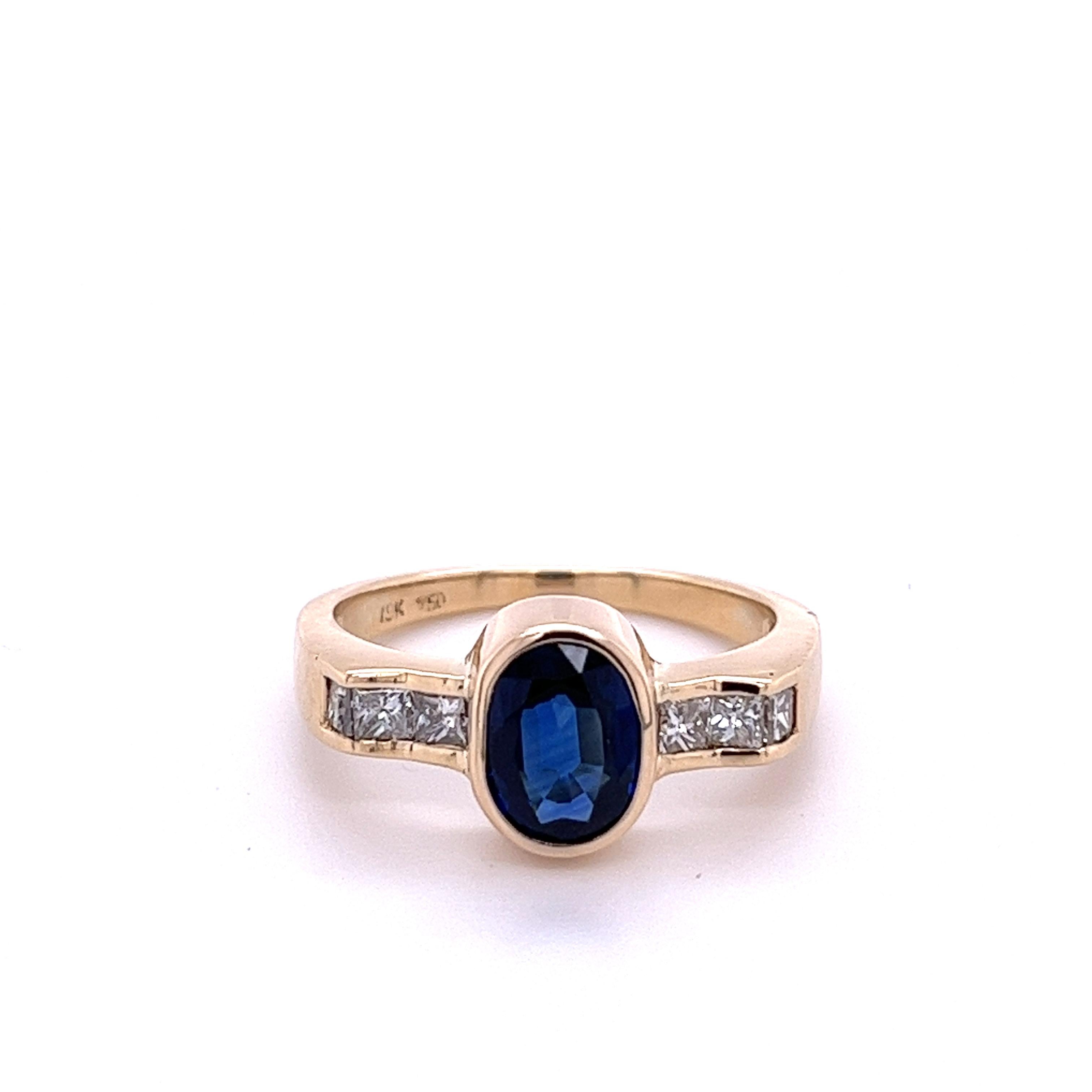 1.48 carat natural oval-cut Blue Sapphire set with 0.30 carats in princess-cut natural diamonds. The Blue Sapphire is mounted in an 18k yellow gold bezel setting with tension set diamonds. The bezel setting provides excellent color contrast to the