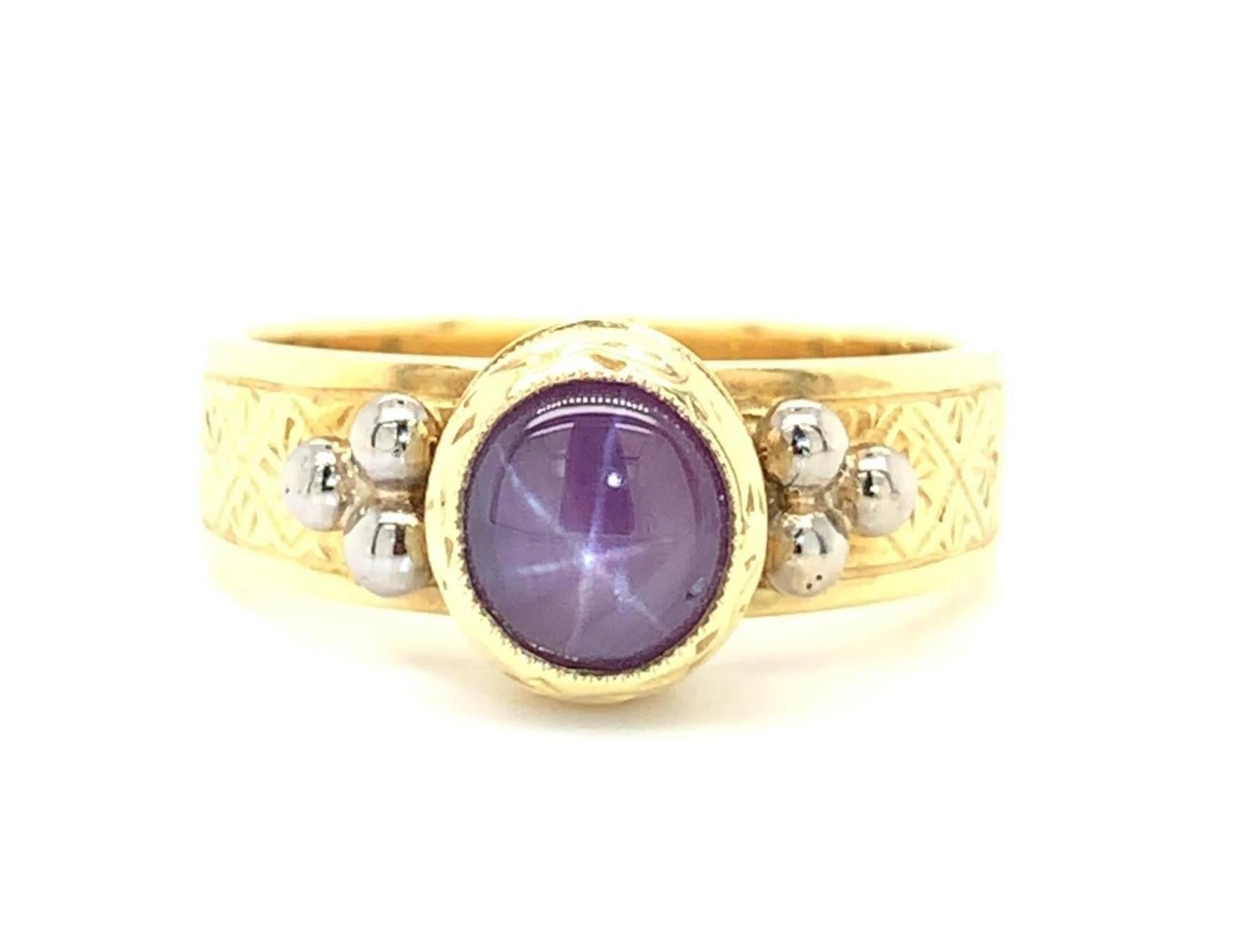 This original ring features a 1.48 carat star ruby cabochon set in a beautifully hand-engraved 18k yellow gold bezel. The ruby is a rich purplish red color and exhibits a lovely, well defined 6-rayed star. It is showcased in an intricately engraved