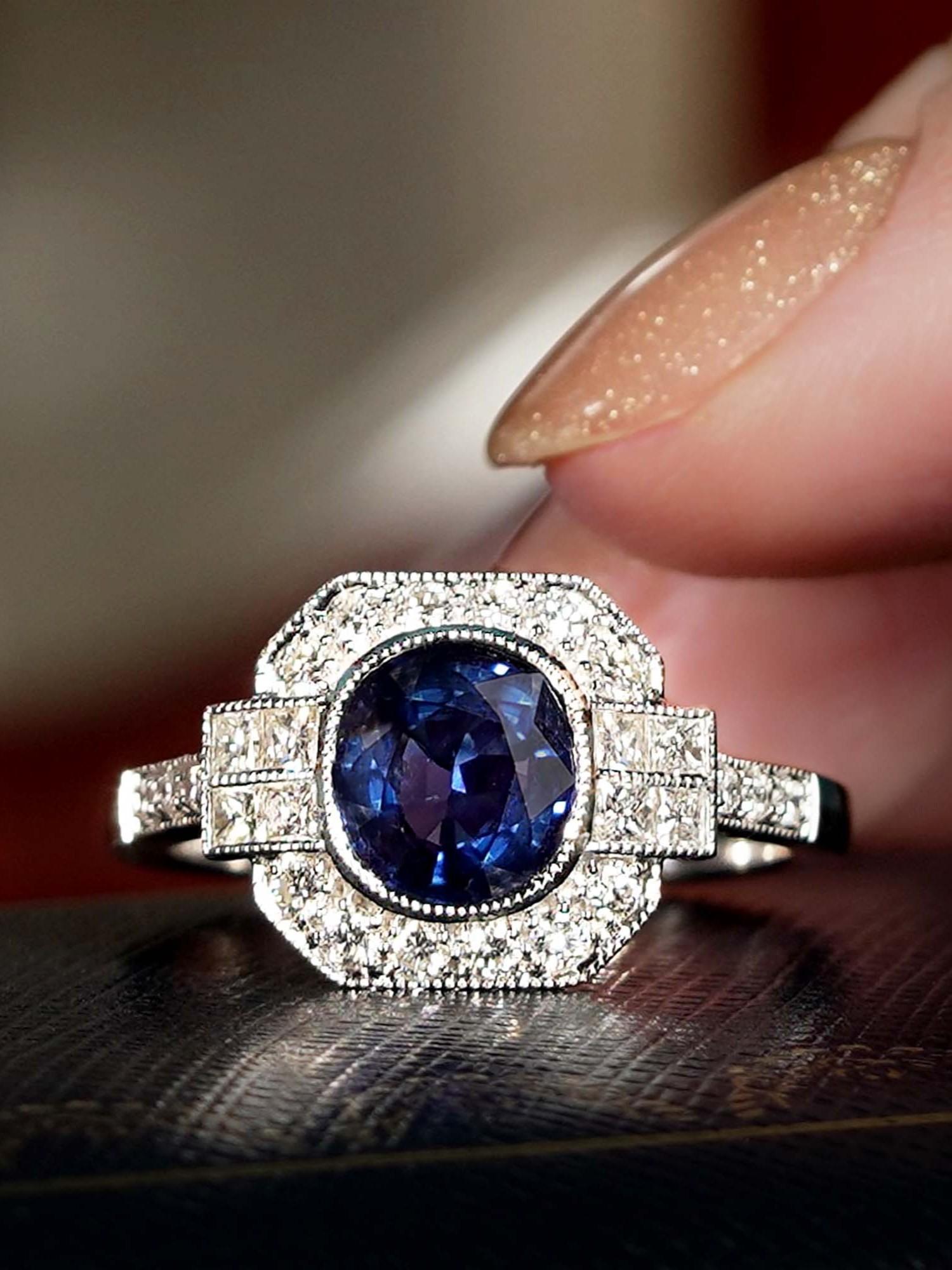 Un cautivador zafiro de Madagascar en forma de cojín de 1,48 en el centro, rodeado de un brillante halo de diamantes. El diseño geométrico realza el azul vibrante del zafiro, creando un aspecto atrevido pero elegante. La combinación de rico color y