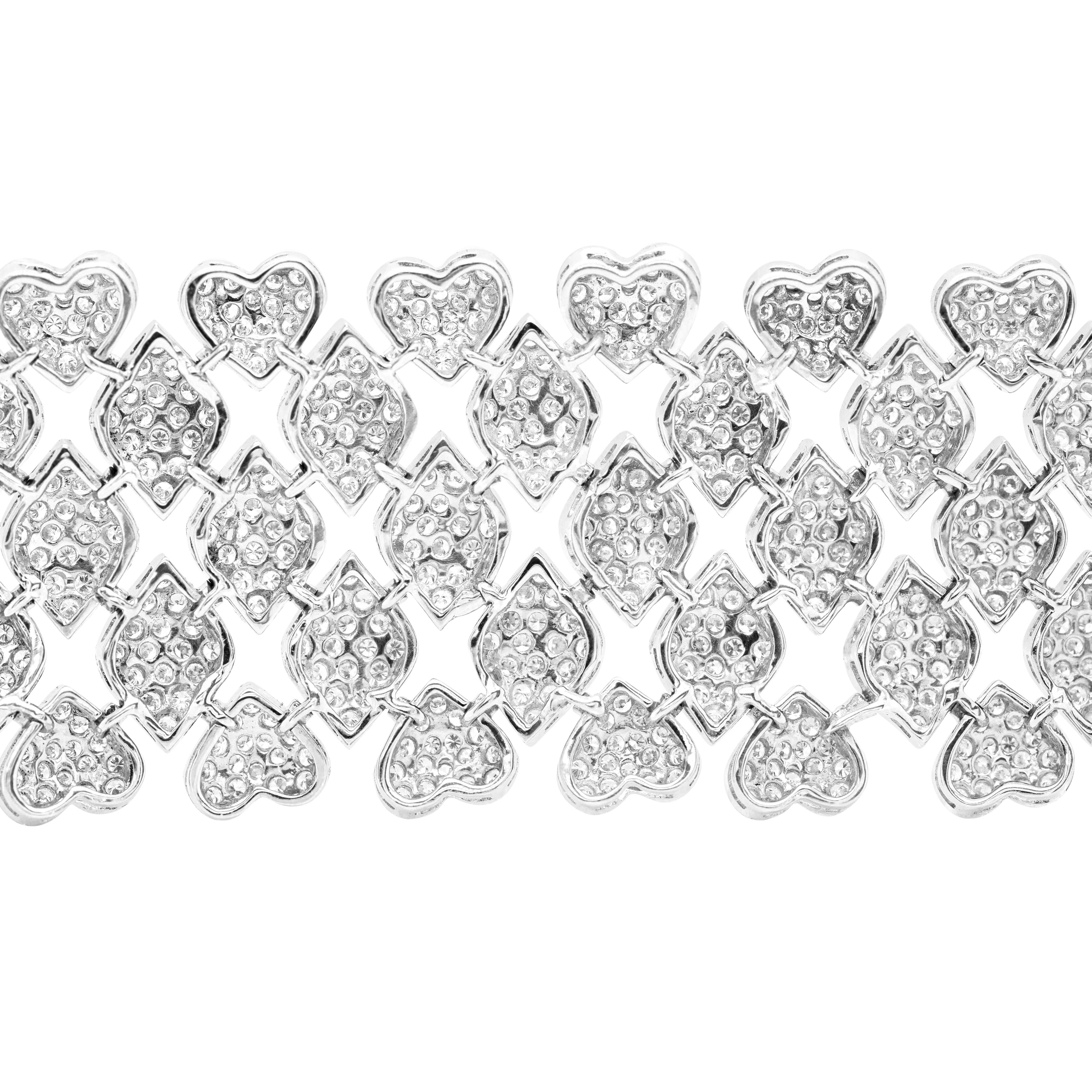 This luxurious 18 carat white gold cuff bracelet features a grand total of 1440 fine round brilliant cut diamonds totalling to an impressive weight of 14.80 carats, all grain set throughout the bracelet on heart and diamond shaped links. The
