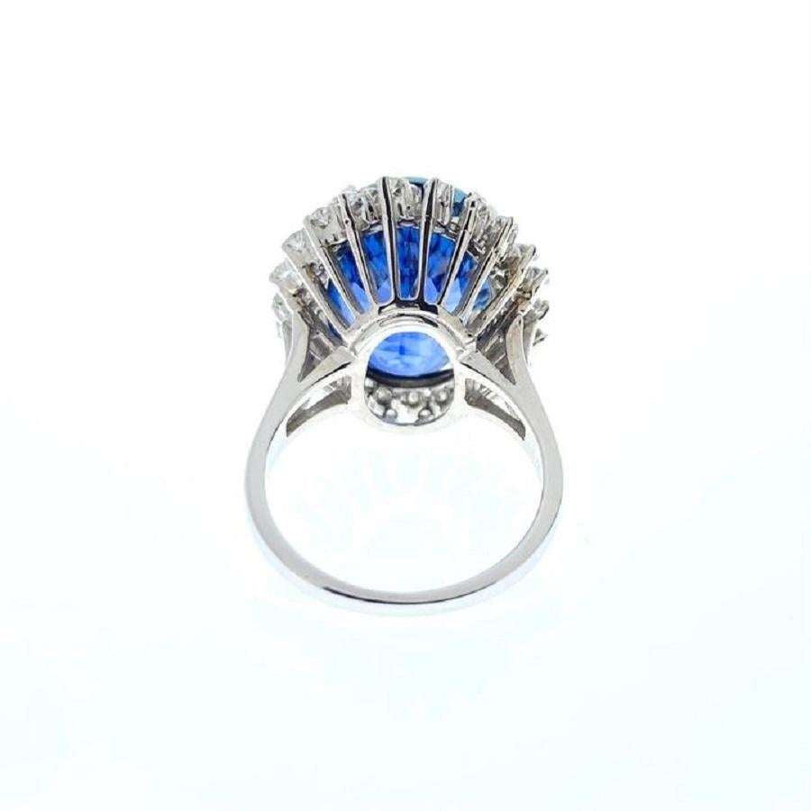 This stunning ring boasts a centerpiece that captures attention with its elegance and allure. Crafted in 14 karat white gold, it features a magnificent 14.87 carat oval-shaped blue sapphire at its heart, radiating a rich, deep hue that exudes