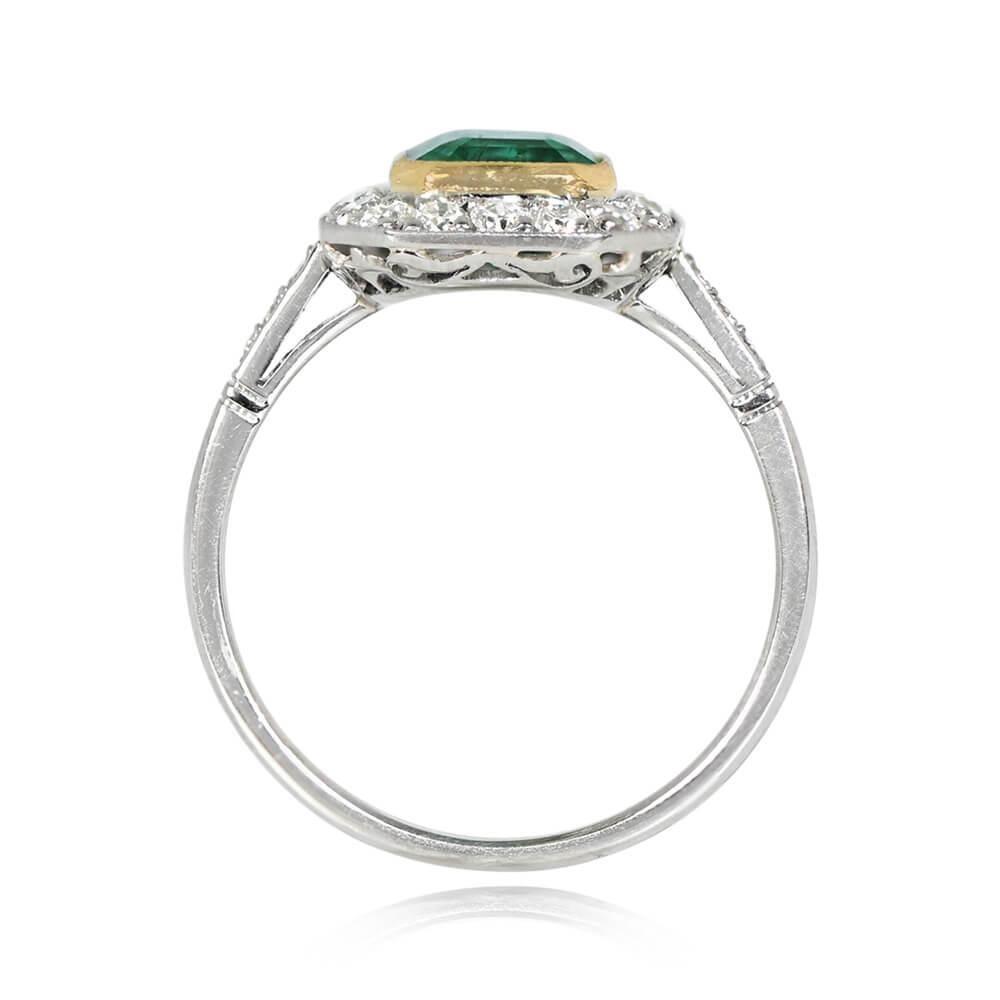 An emerald and diamond halo ring featuring a 1.48-carat emerald-cut natural emerald, bezel-set in gold. Old European cut diamonds encircle the emerald and adorn the shoulders. The total diamond weight is around 0.45 carats. Crafted in 18k yellow