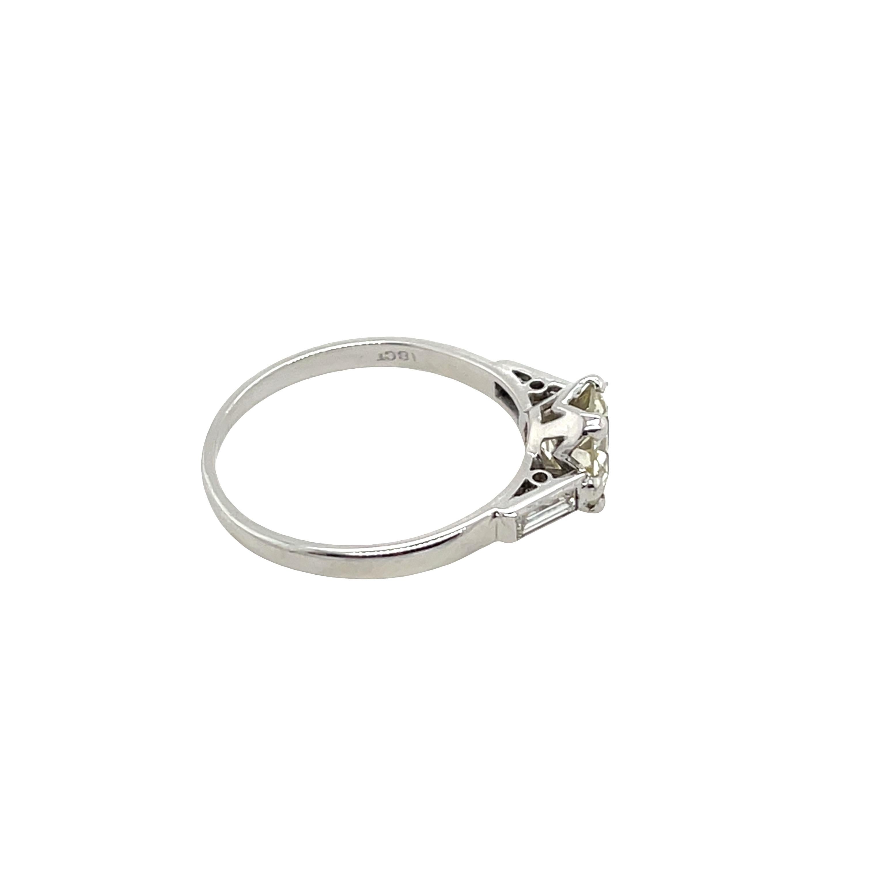 Ein atemberaubender Diamantring mit 1,48 Karat rundem Brillantschliff, gefasst in 18 Karat Weißgold. Der Diamant ist in der Farbe Q-R und in der Reinheit I1 eingestuft und bietet ein wunderschönes Funkeln, flankiert von Baguette-Diamanten auf jeder