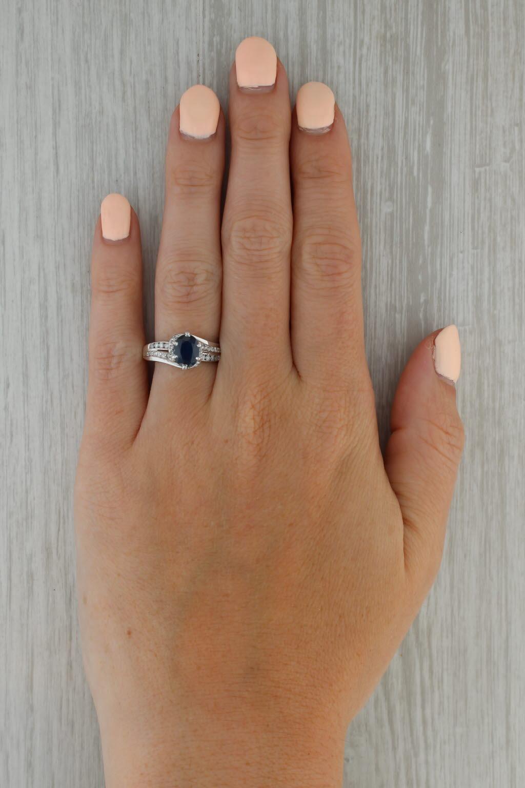 Gemstone Information:
- Natural Sapphire -
Carats - 1.32ct 
Cut - Oval 
Color - Dark Blue
Treatment - Heated

- Natural Diamonds -
Total Carats - 0.16ctw
Cut - Round Brilliant
Color - F - G
Clarity - I1 - I2

Metal: 14k White Gold
Weight: 5 Grams