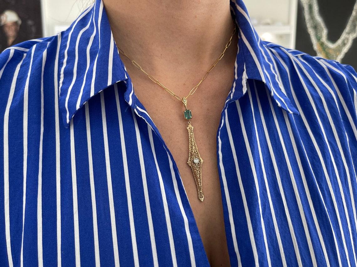 Step back in time with our exquisite Natural Emerald & Diamond Accent Edwardian 1910s Vintage-Inspired Pendant Necklace, a true embodiment of timeless elegance. This enchanting pendant features an emerald cut emerald that gracefully dangles below